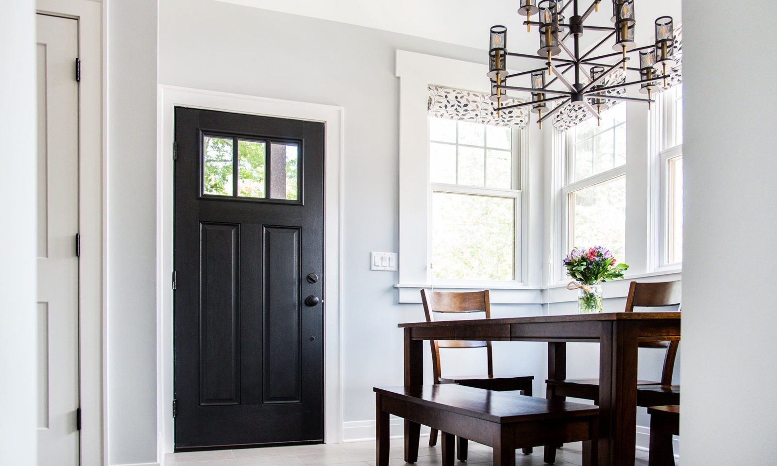 Newly renovated kitchen with dark statement kitchen door, modern chandelier, dark table, and light color walls