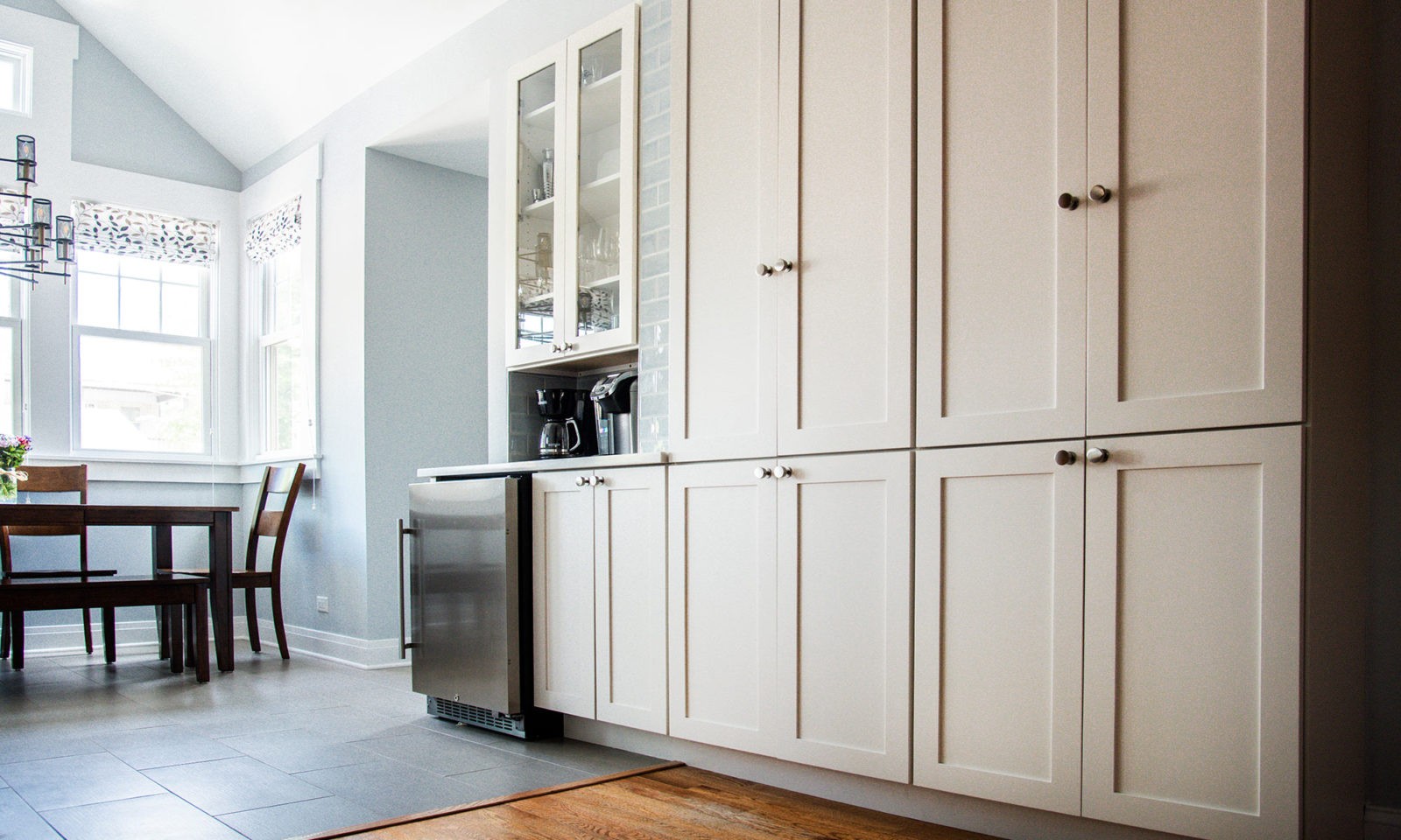 Newly renovated kitchen with cream cabinets, glass cabinet doors, stainless steel appliances, wood and tile floors