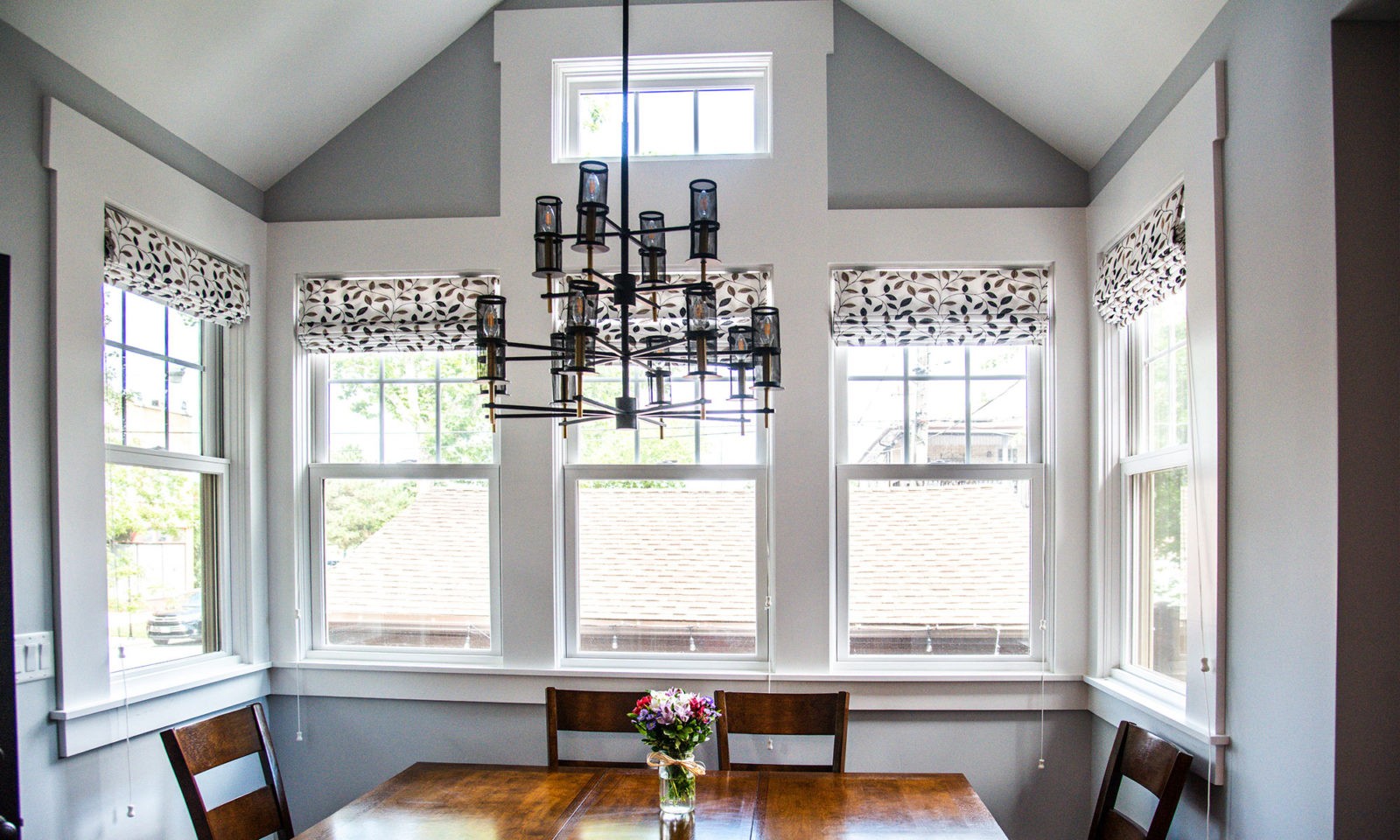 6 bright windows on the walls of a newly renovated kitchen with a chandelier and a dark wooden table