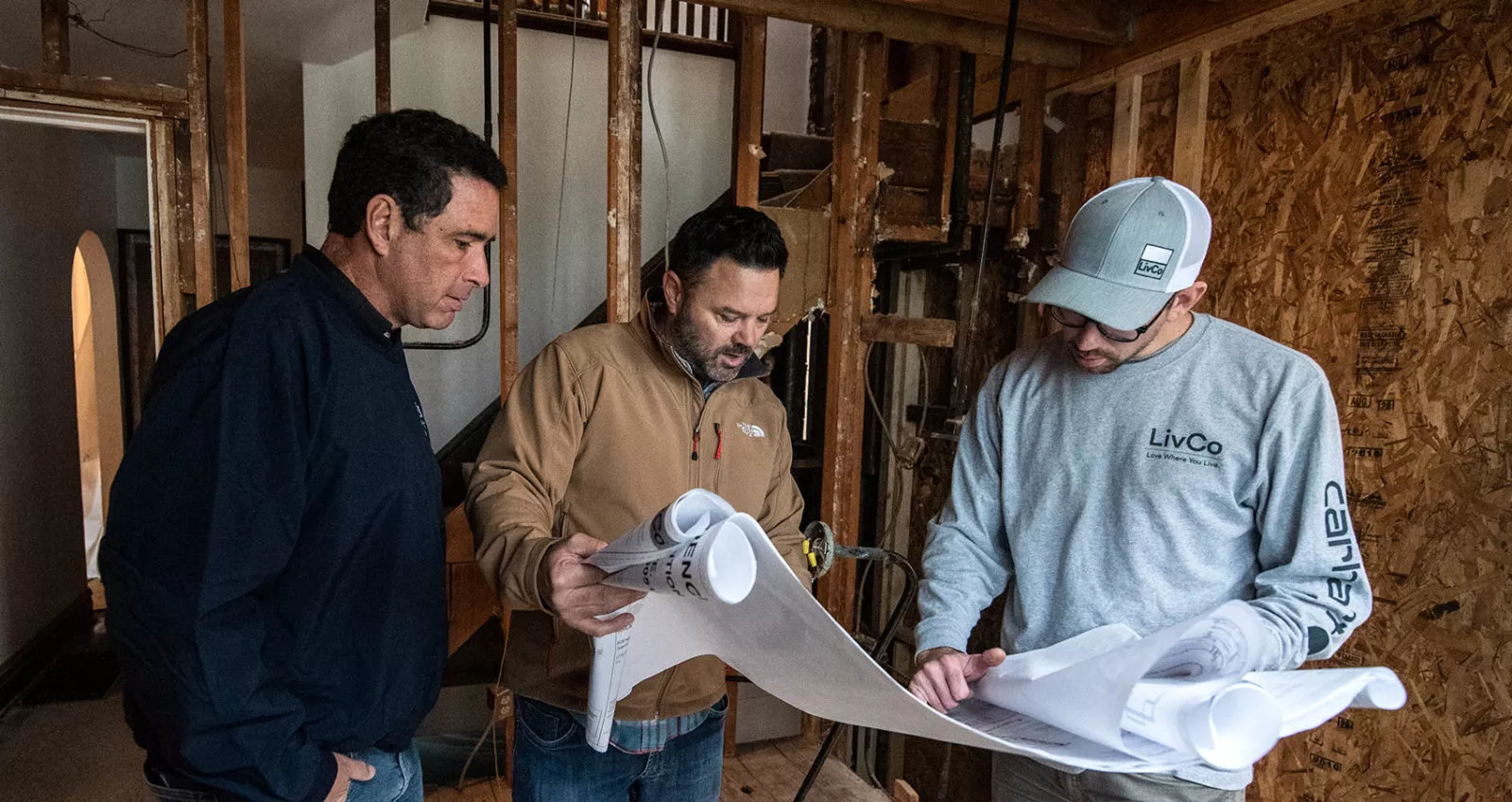 architect and builder reviewing blueprints on a jobsite for a home remodel