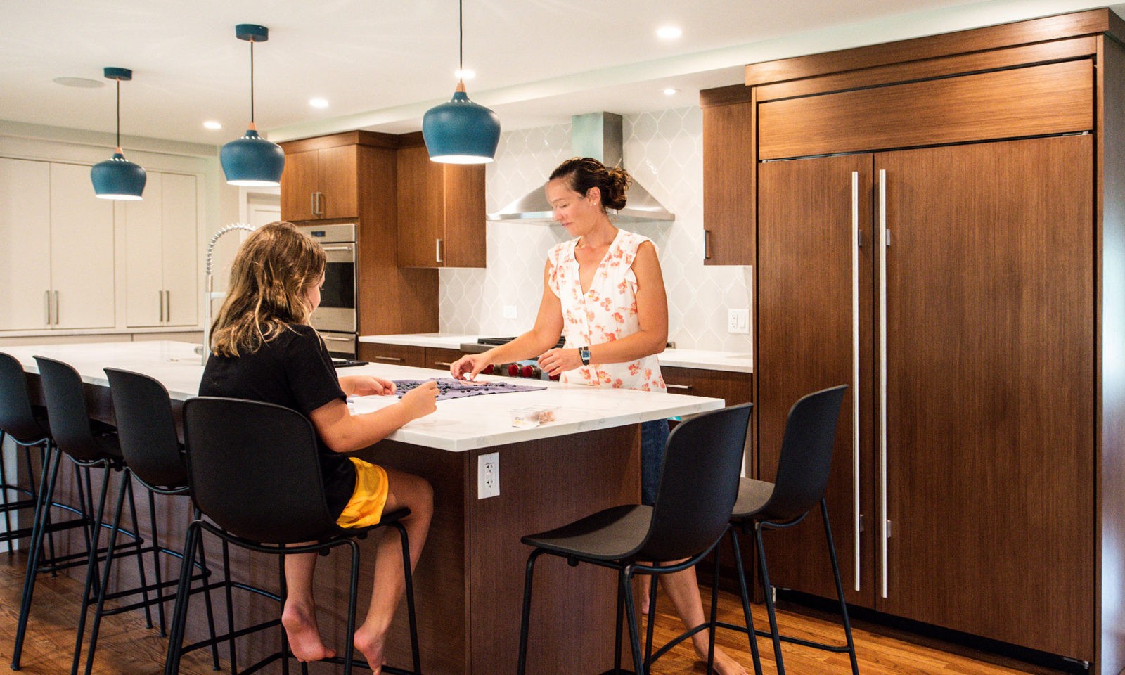 family in a modern hinsdale kitchen remodel with white counters and blue pendant lights