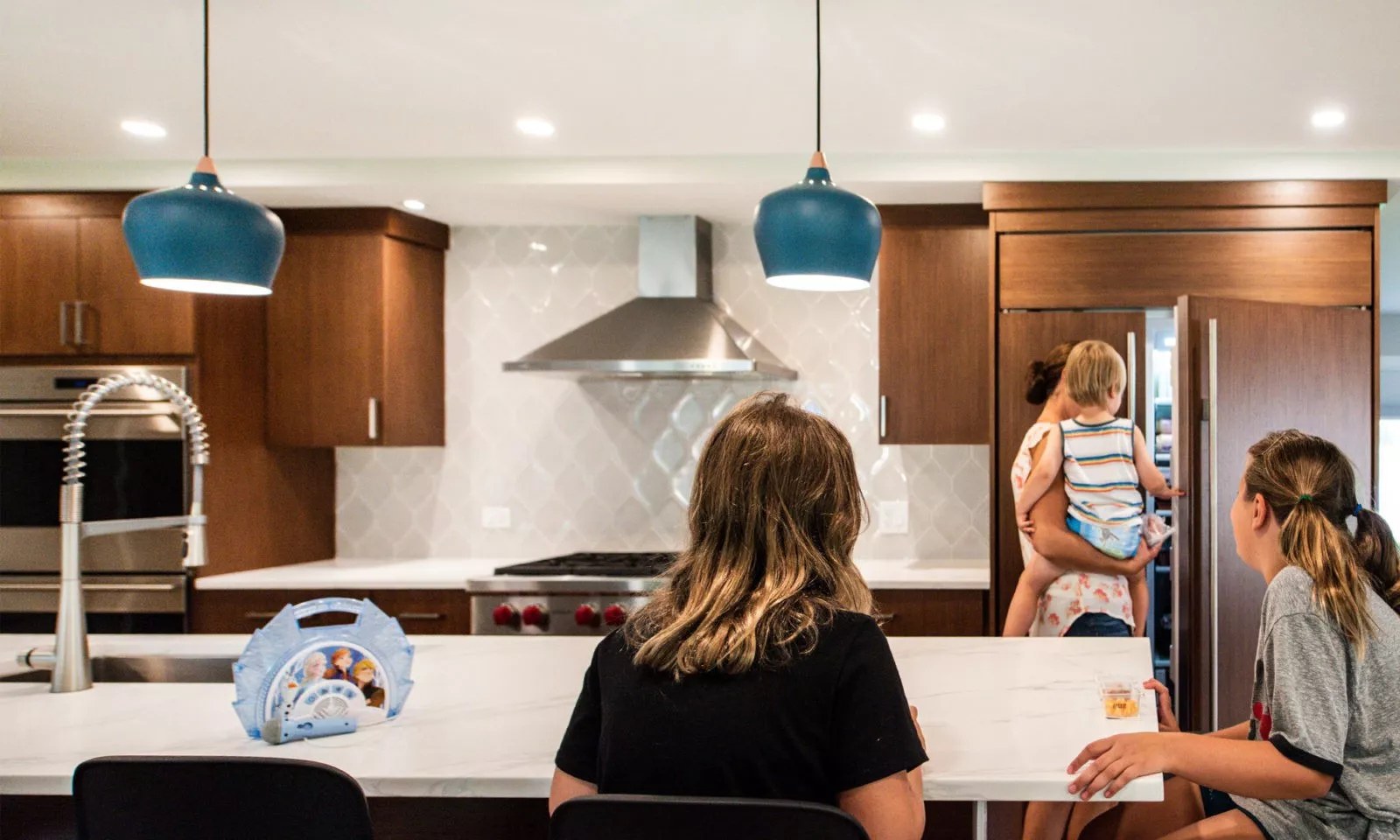 family in a modern hinsdale kitchen remodel with white counters and blue pendant lights