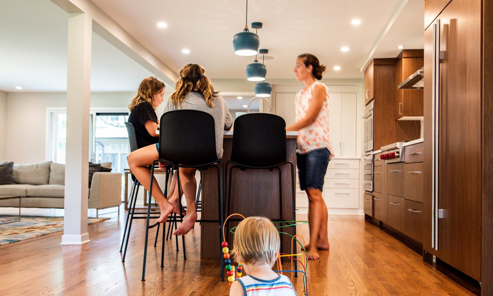 family in a modern hinsdale kitchen remodel with white counters and blue pendant lights