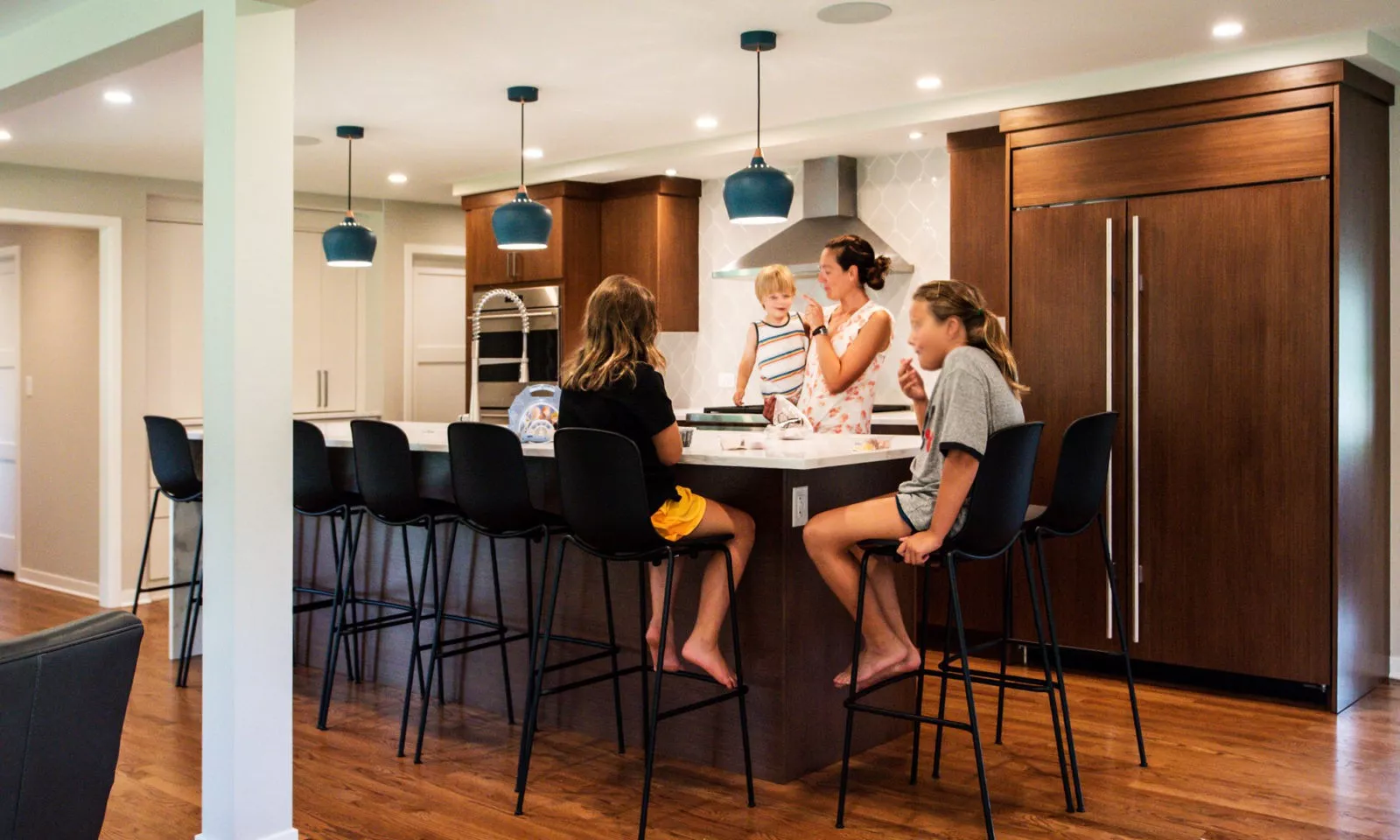 family in a modern hinsdale kitchen remodel with white counters and blue pendant lights