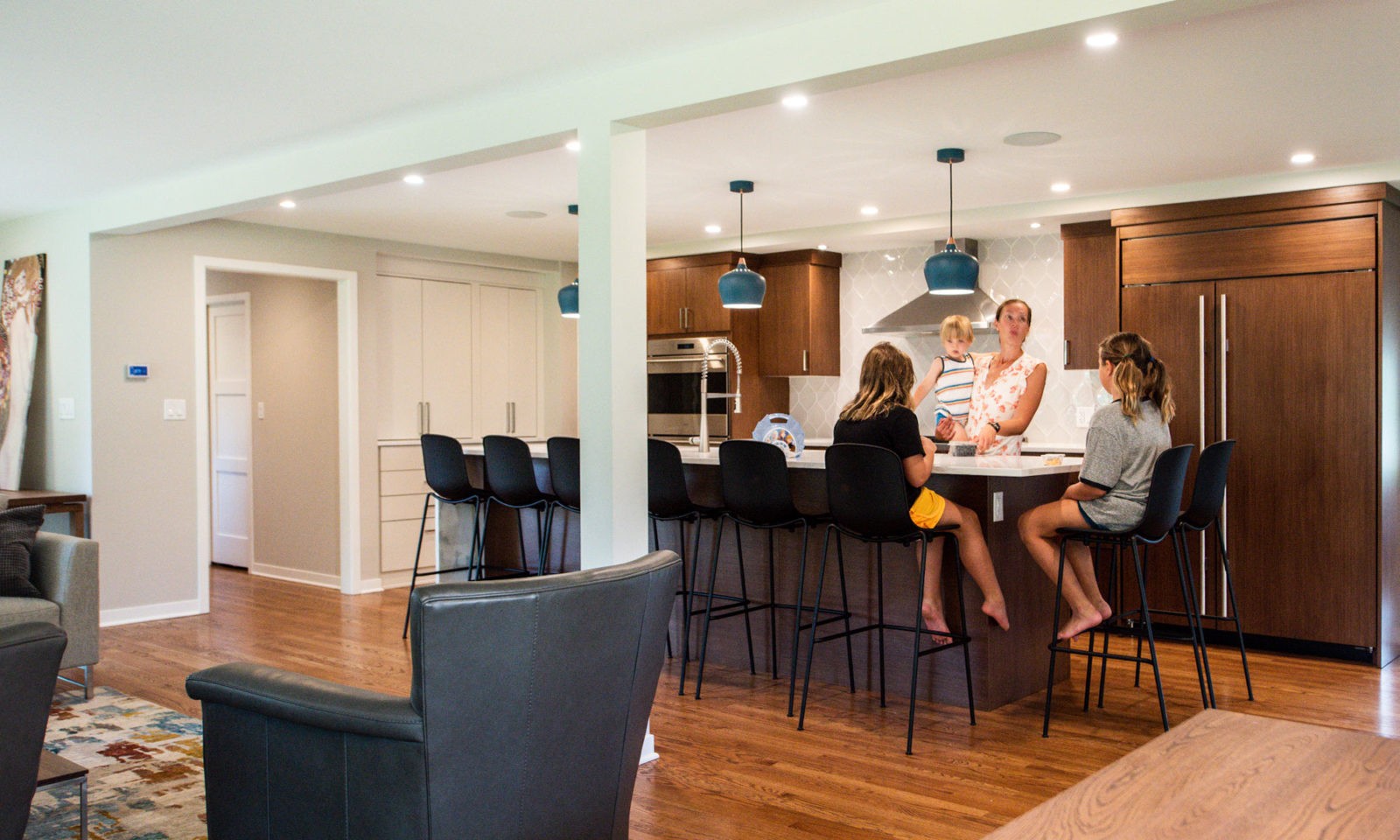 family in a modern hinsdale kitchen remodel with white counters and blue pendant lights