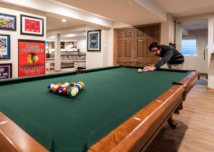 basement renovation with man playing pool in mancave over hardwood floors recess lighting