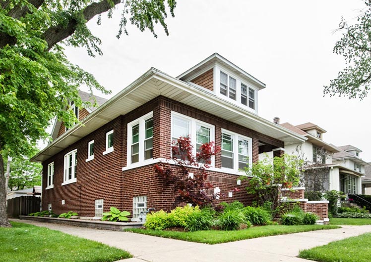 exterior view of whole home remodel brick home with porch white framed windows and simple landscping