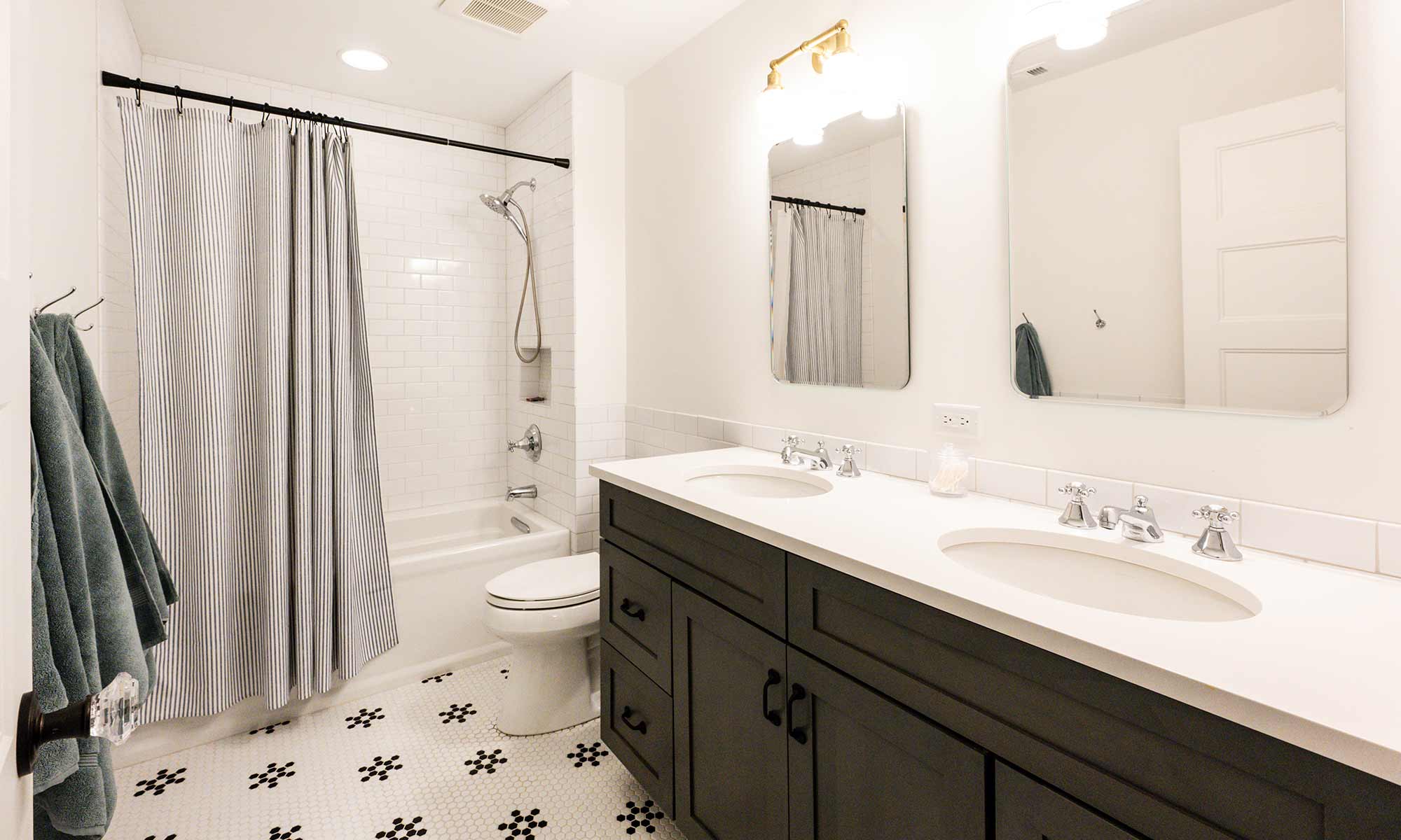 bathroom remodel with grey double vanity and white black hex tile