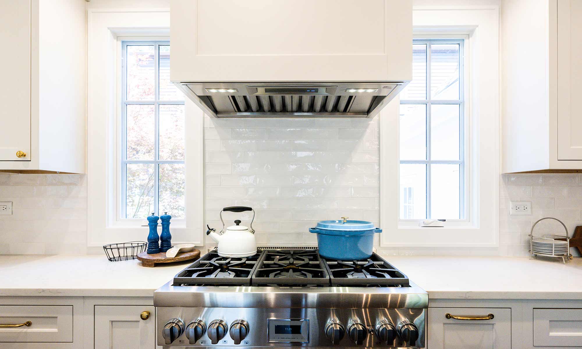 view of luxury kitchen remodel range flanked by casement windows