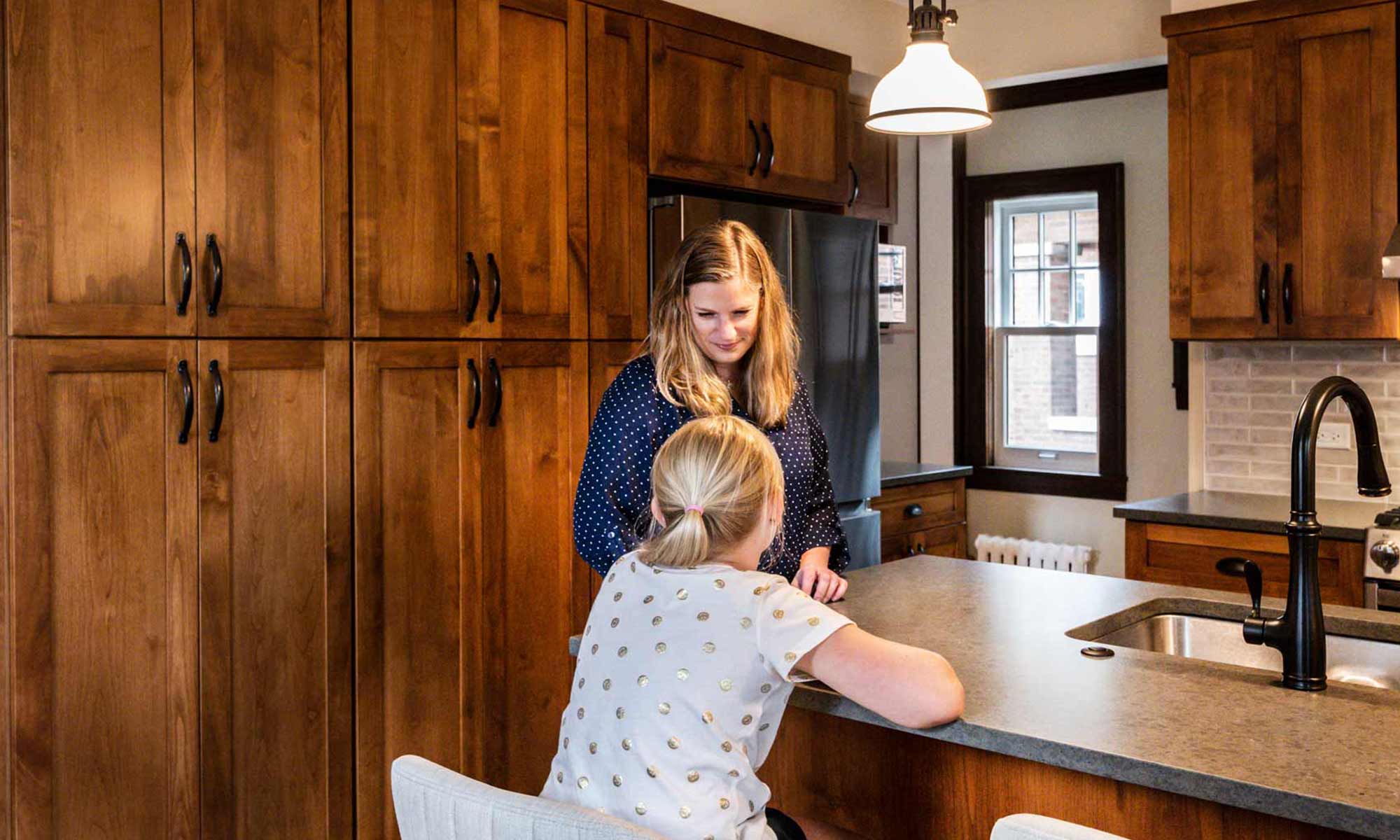 mom and daughter in newly remodeled kitchen with dark wood cabinets