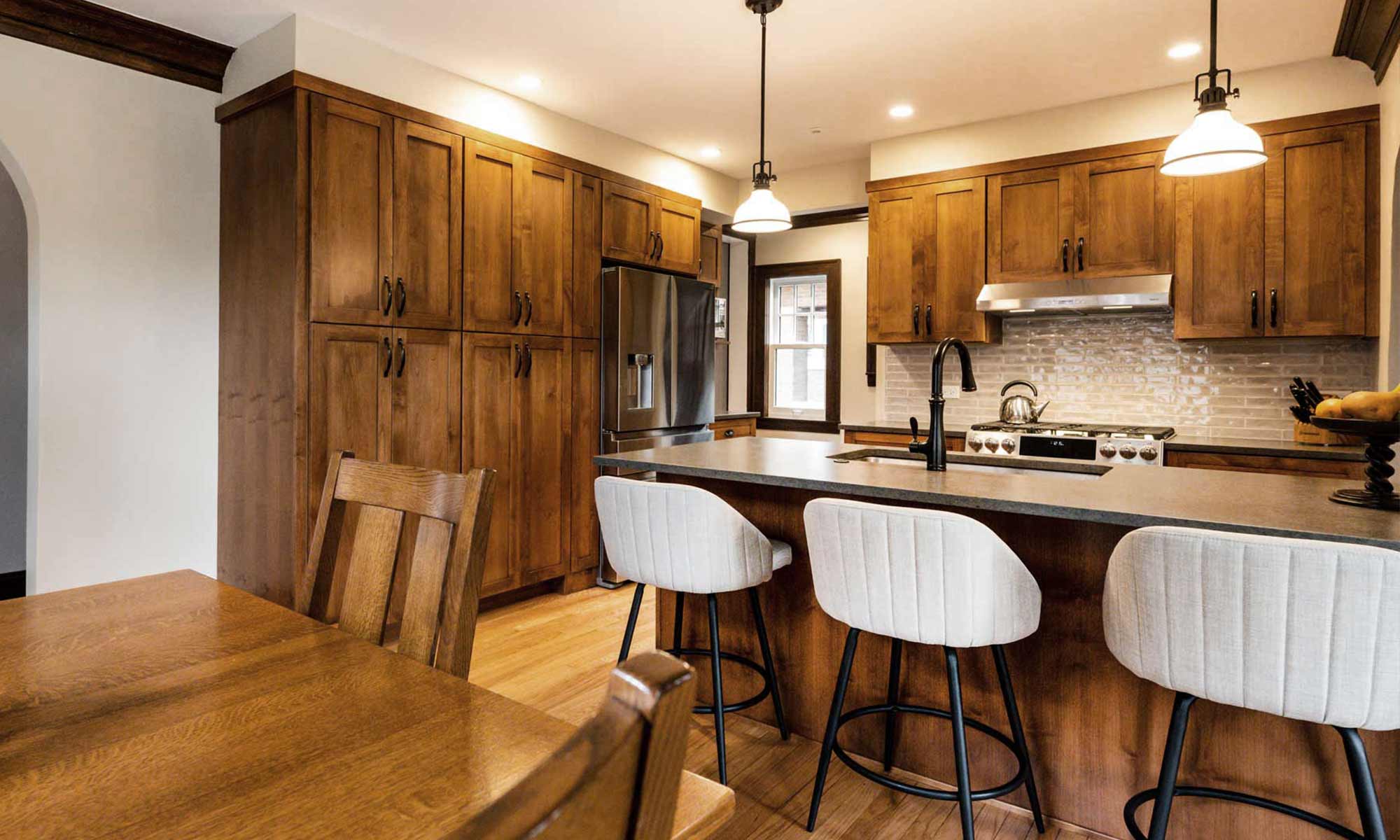 dark wood kitchen cabinets with peninsula seating and tall pantry cabinets