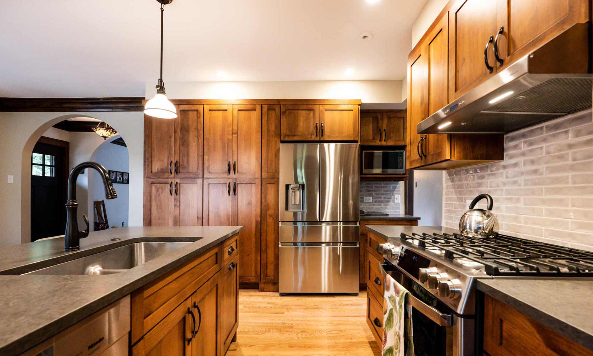 dark wood kitchen cabinets with peninsula seating and tall pantry cabinets