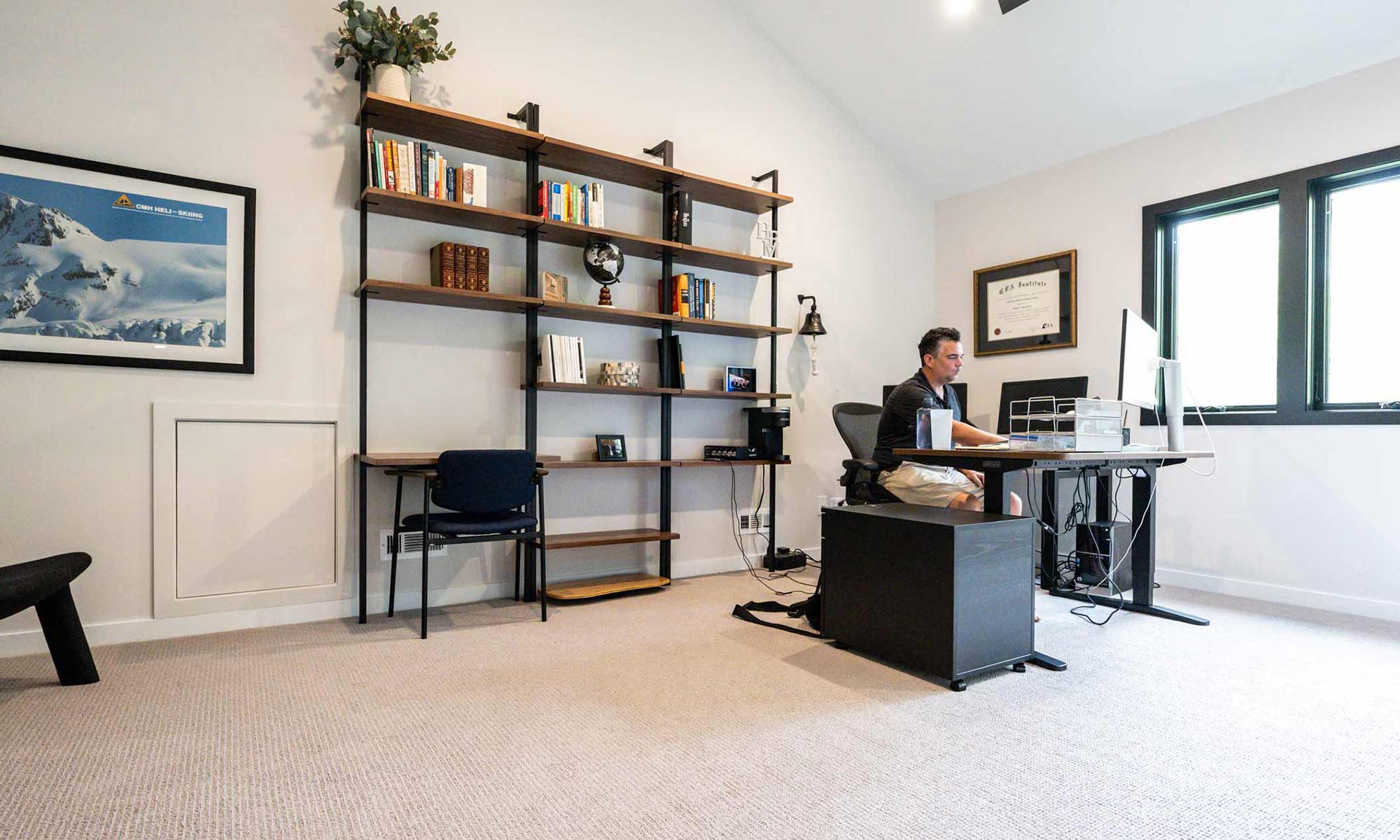 interior view of modern shelves and desk in home office addition with man working