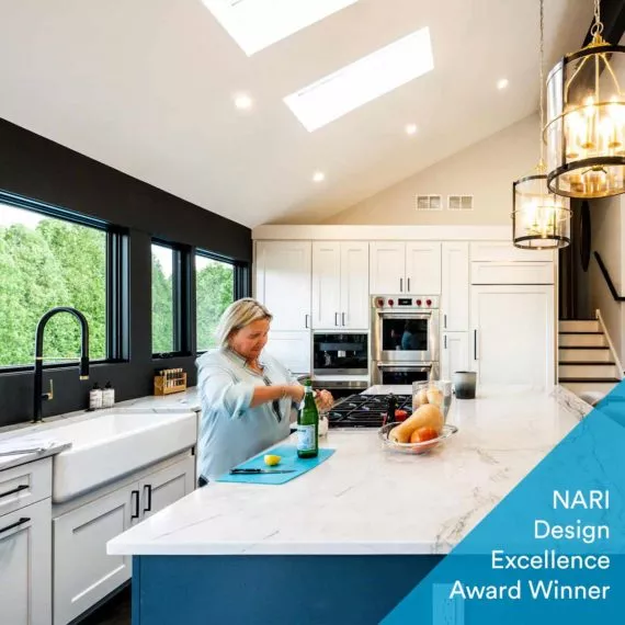 woman opening sparkling water bottle in newly remodeled luxury kitchen with a blue island