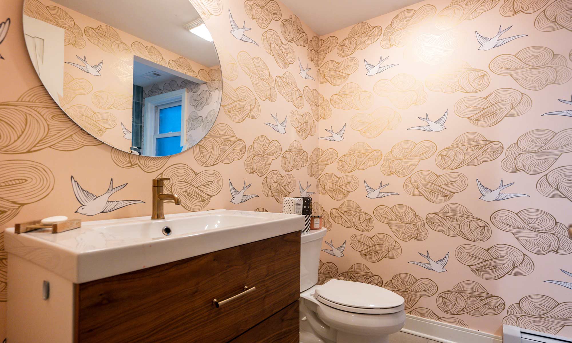 modern remodeled bathroom with pink wallpaper and walnut vanity