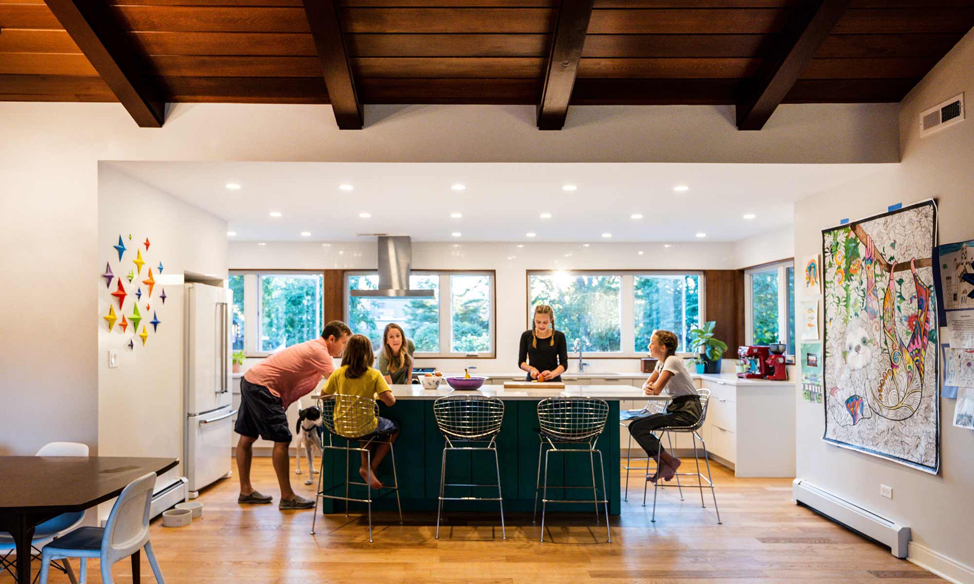 family standing around a green kitchen island in a mid century modern luxury addition