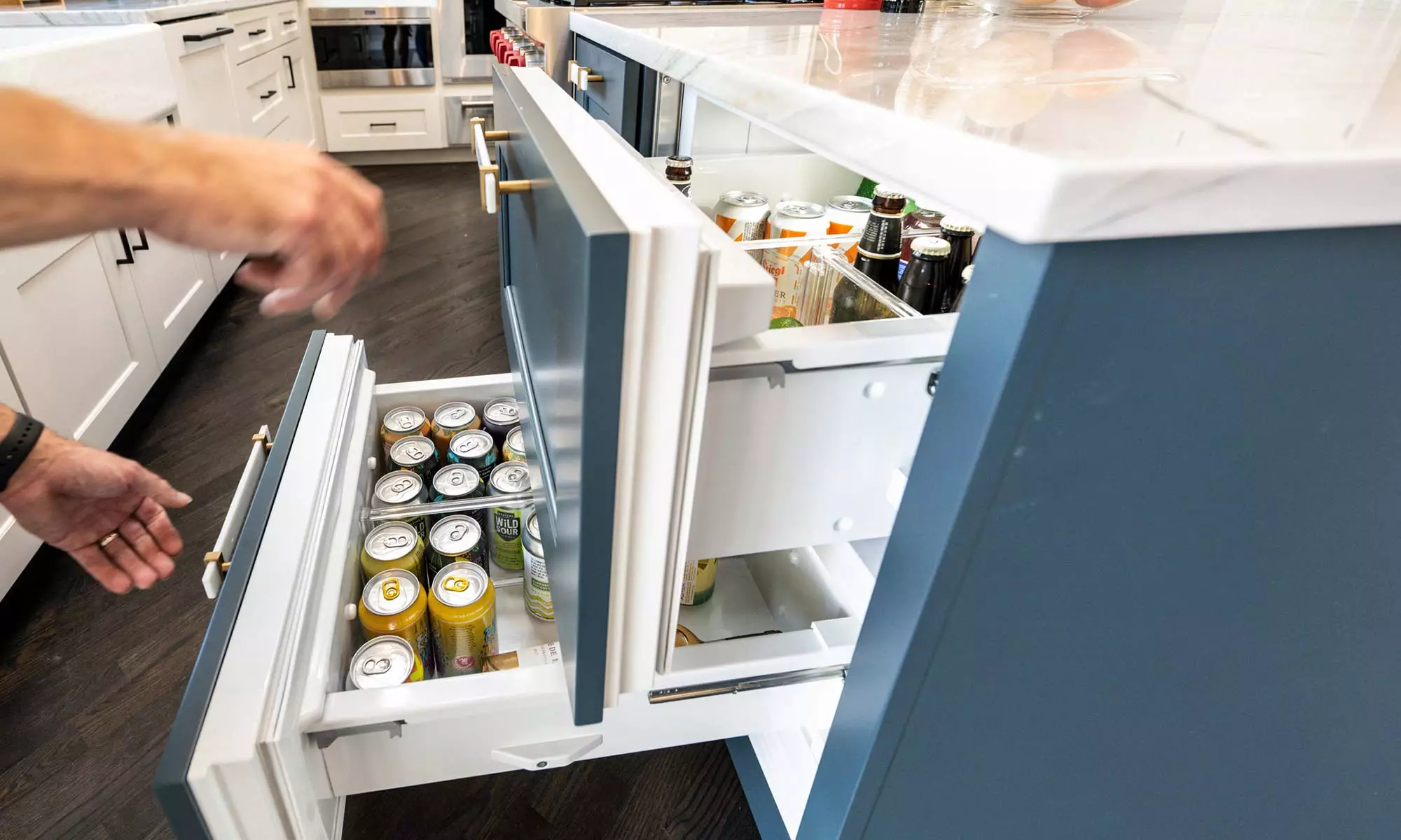 man opening refrigerated drawers in a luxury kitchen remodel with blue island