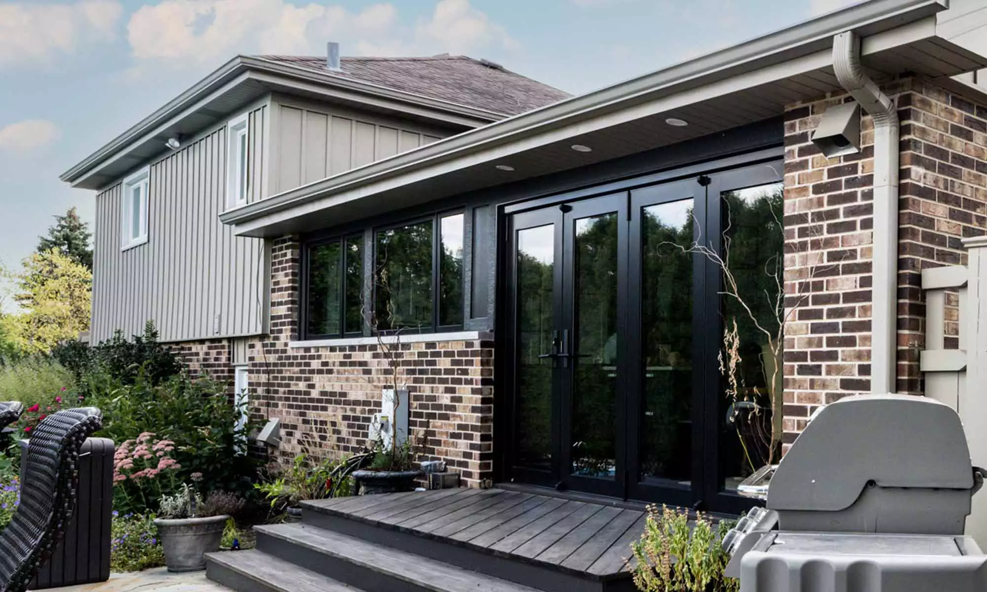 exterior view of remoeled home with brick and glass and folding glass door