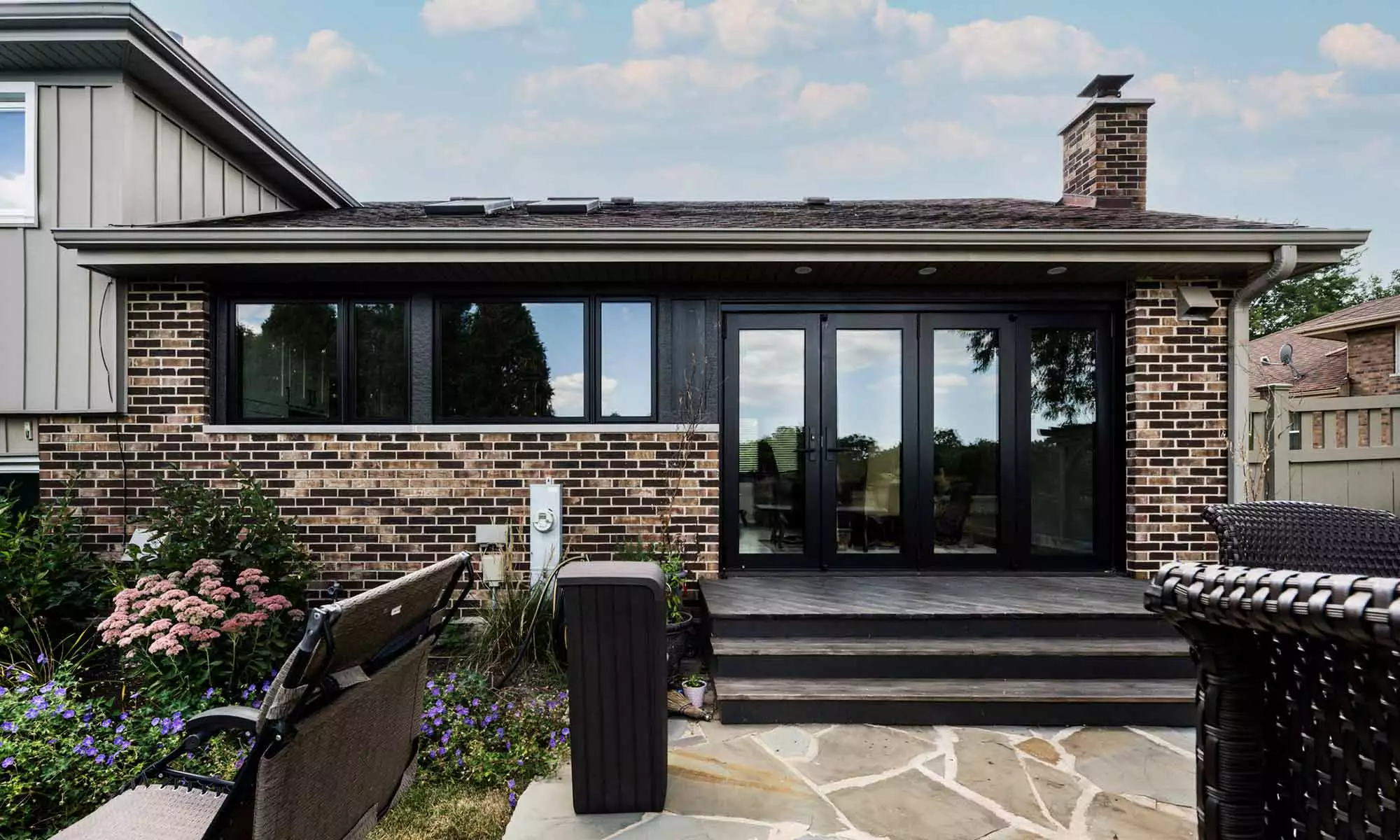 exterior view of remoeled home with brick and glass and folding glass door