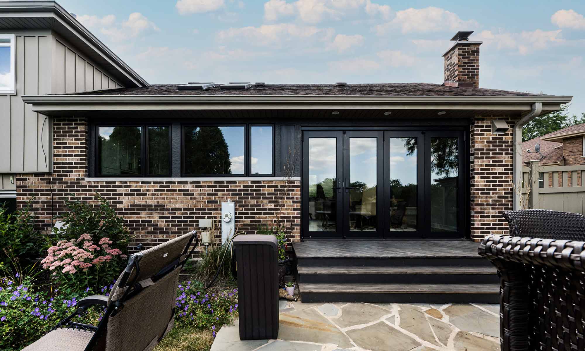 exterior view of remoeled home with brick and glass and folding glass door