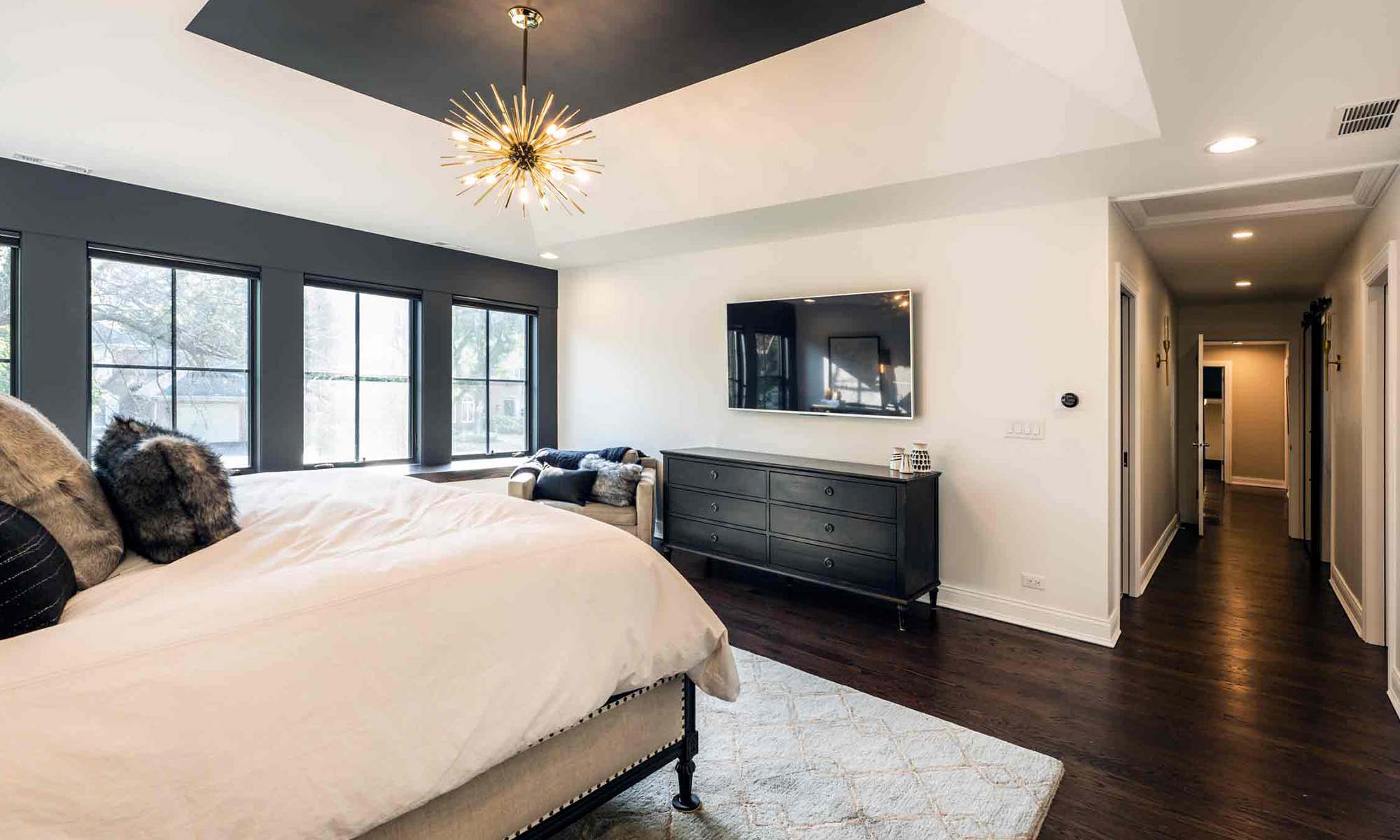 primary suite addition with dark tray ceilings and tv wall