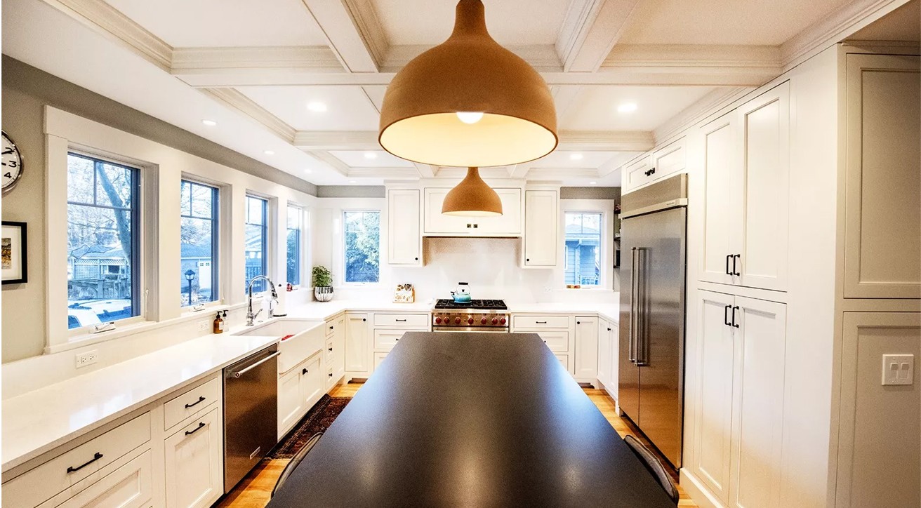 Kitchen with island, chairs, silver appliances, white cabinets and drawers, exterior windows