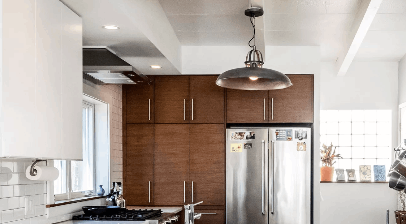 Kitchen with stove, range fan, refrigerator, and brown wood cabinets