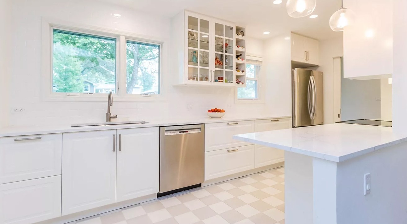 All-white kitchen with extended countertop, cabinets & drawers, silver appliances, 3 windows