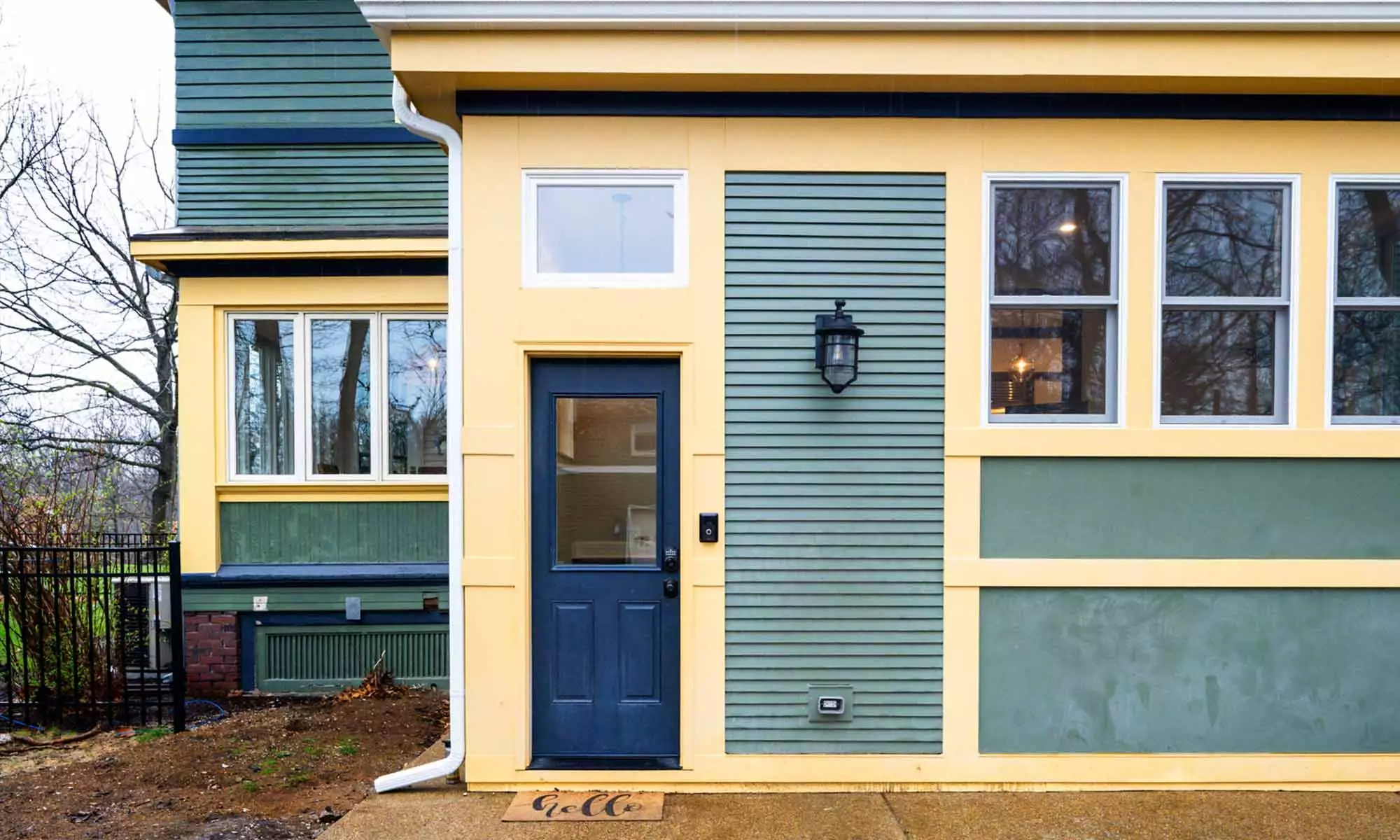 exterior view of mudroom addition with green siding and dark yellow trim
