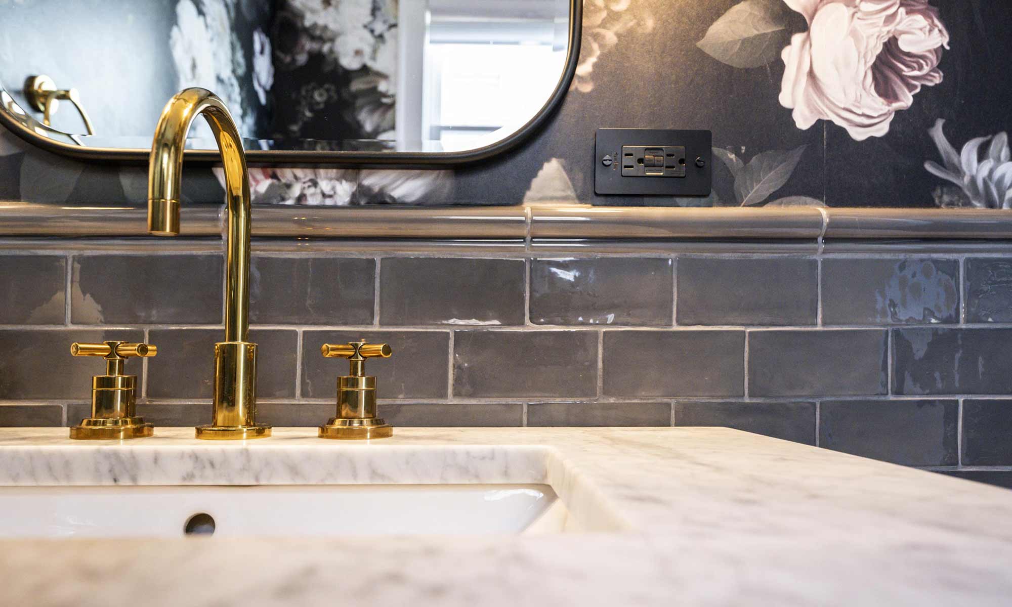 luxuty bathroom remodel with brass pedestal sink, dark subway tile wainscot, and floral wallpaper