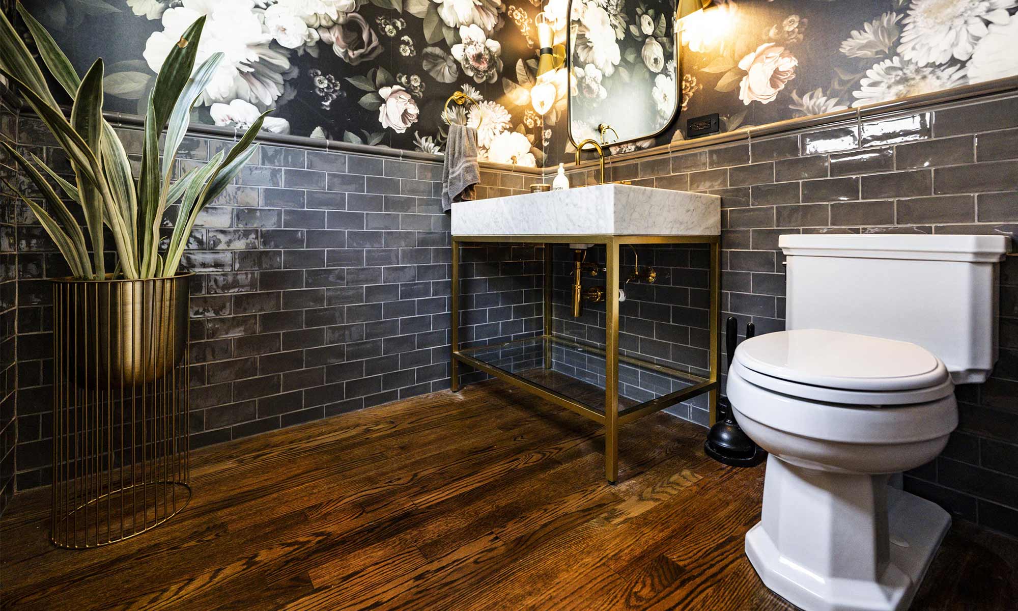luxuty bathroom remodel with brass pedestal sink, dark subway tile wainscot, and floral wallpaper