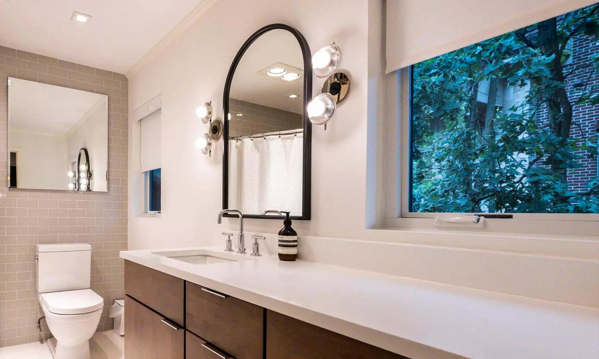 modern bathroom remodel with window and arched mirror