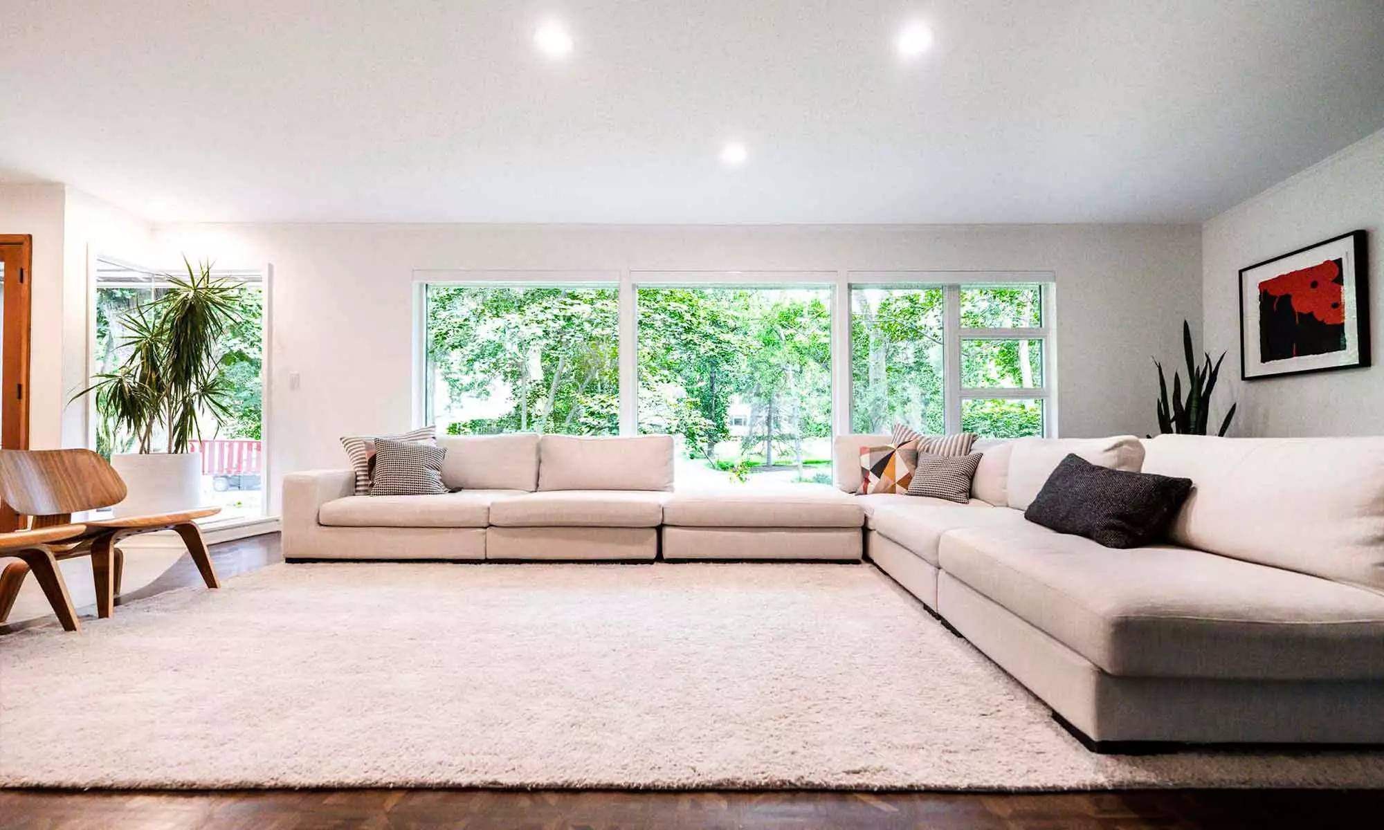 Updated Hinsdale living room with ivory shag rug & large off-white sectional couch in front of a wall of windows