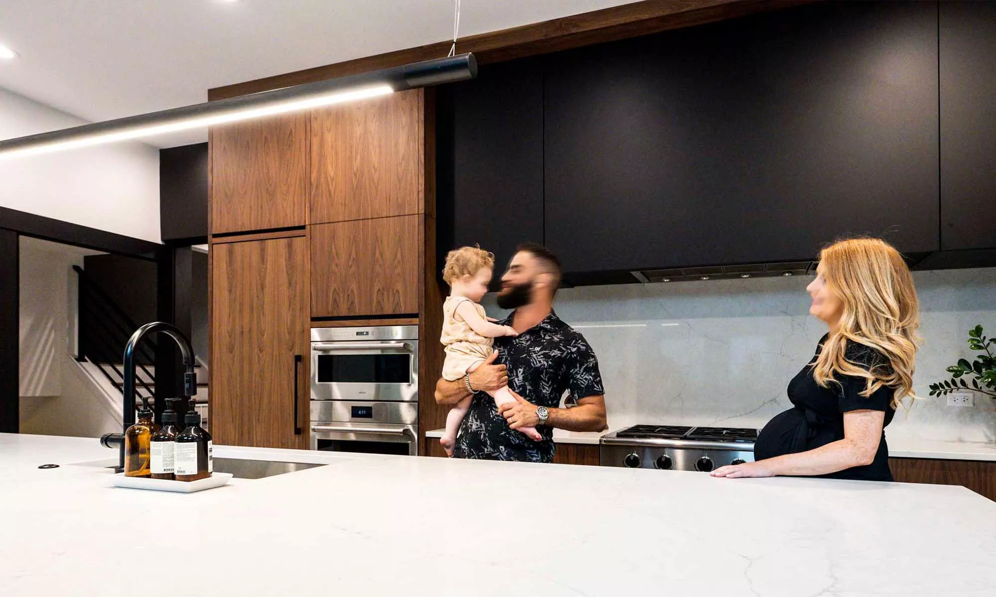 family with baby in modern kitchen remodel by LivCo with vaulted ceiling and walnut cabinets in Hinsdale, illinois