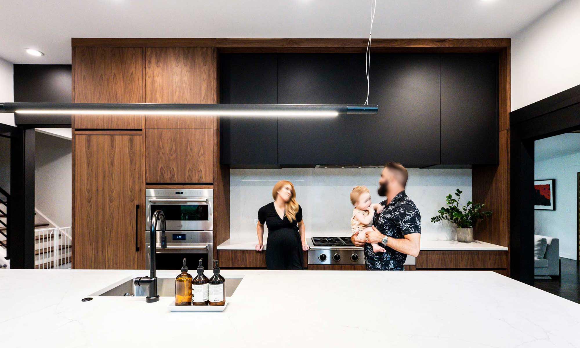 family with baby in modern kitchen remodel by LivCo with vaulted ceiling and walnut cabinets in Hinsdale, illinois
