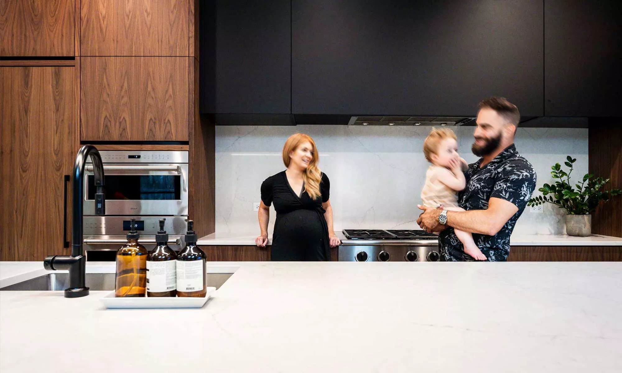 family with baby in modern kitchen remodel by LivCo with vaulted ceiling and walnut cabinets in Hinsdale, illinois