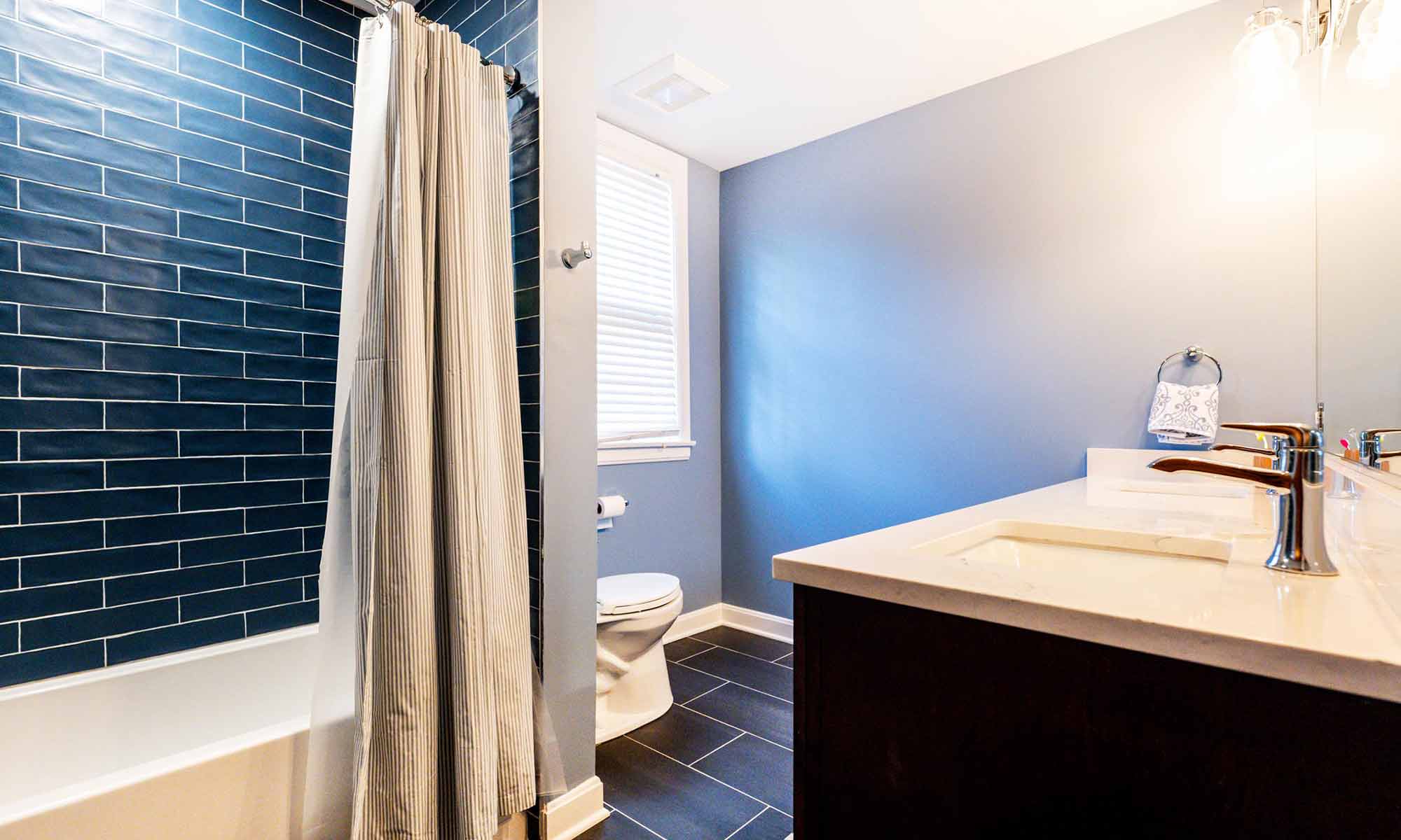 Updated blue bathroom with deep blue subway-tiled shower