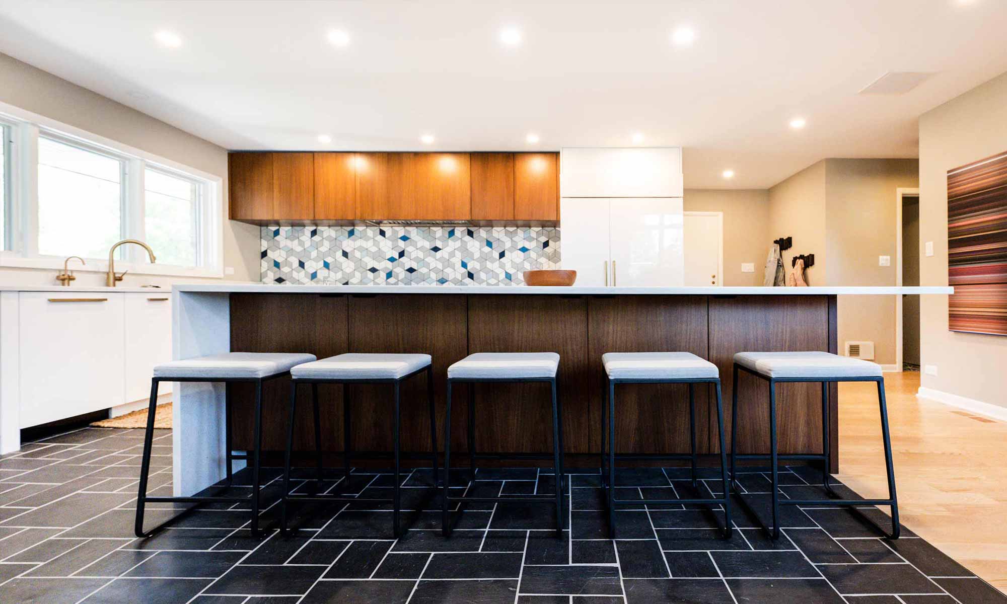 view of barstools at walnut kitchen island with backsplash and wall cabinets beyond