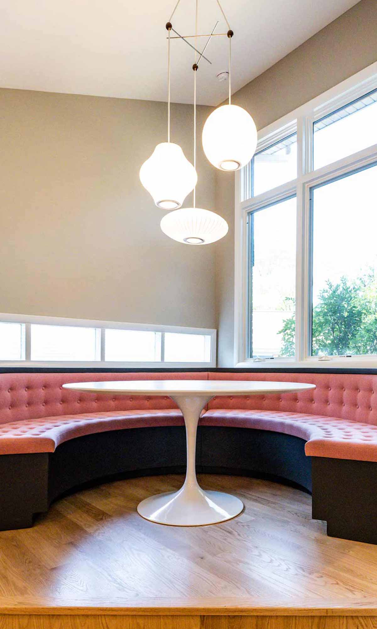 pink upholstered round corner booth seating in mid century luxury remodel