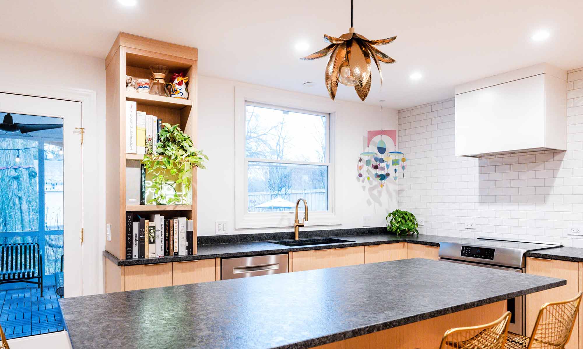 Modern luxury kitchen remodel in Riverside, IL with white oak cabinets and black stone countertops and open shelves with a plant and rondelay mobile hanging from ceiling