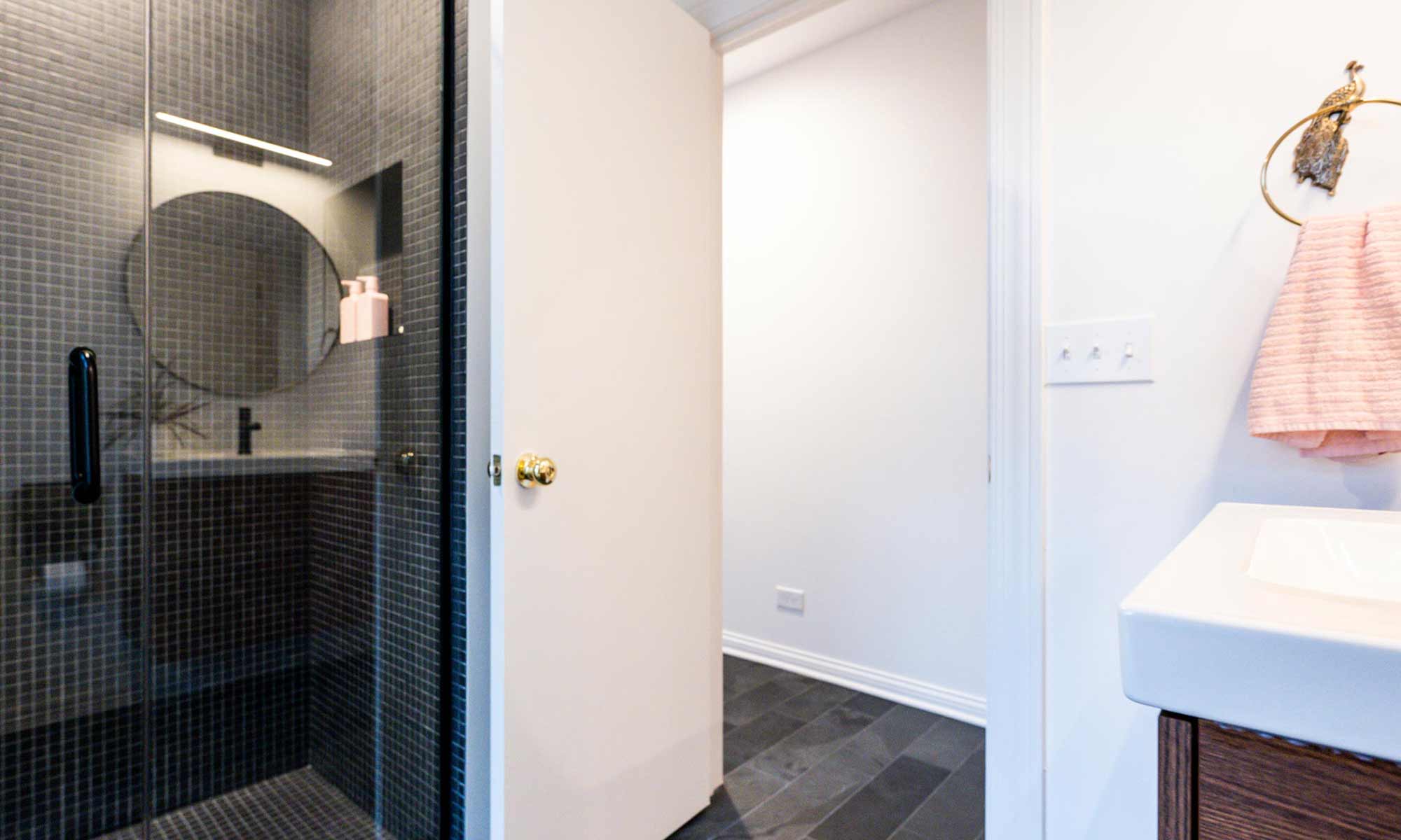 view looking out of bathroom to hallway with black mosaic walltile