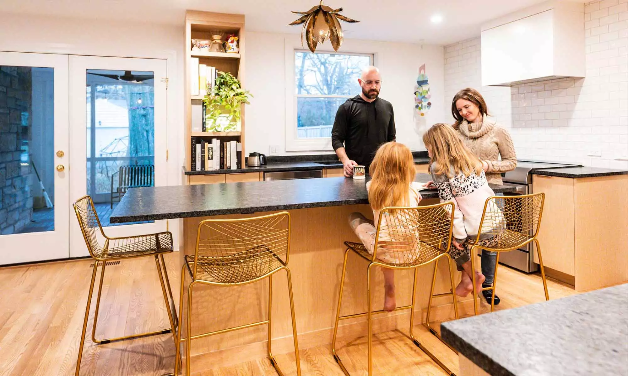 Family gathered around white oak island with black stone countertops in luxury Riverside, IL kitchen remodel