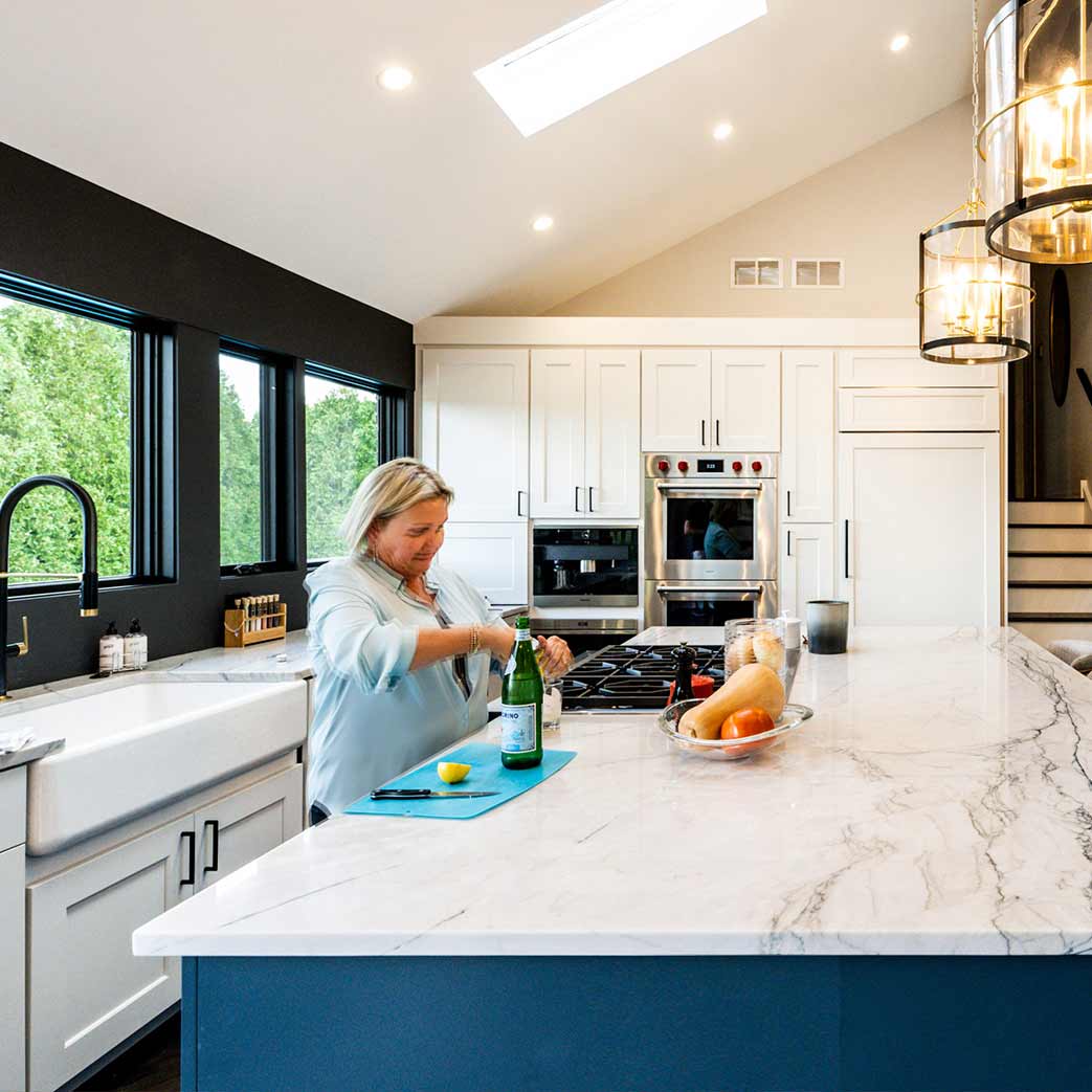 woman cutting a lemon and preparing drink at kitchen island in downers grove luxury remodel