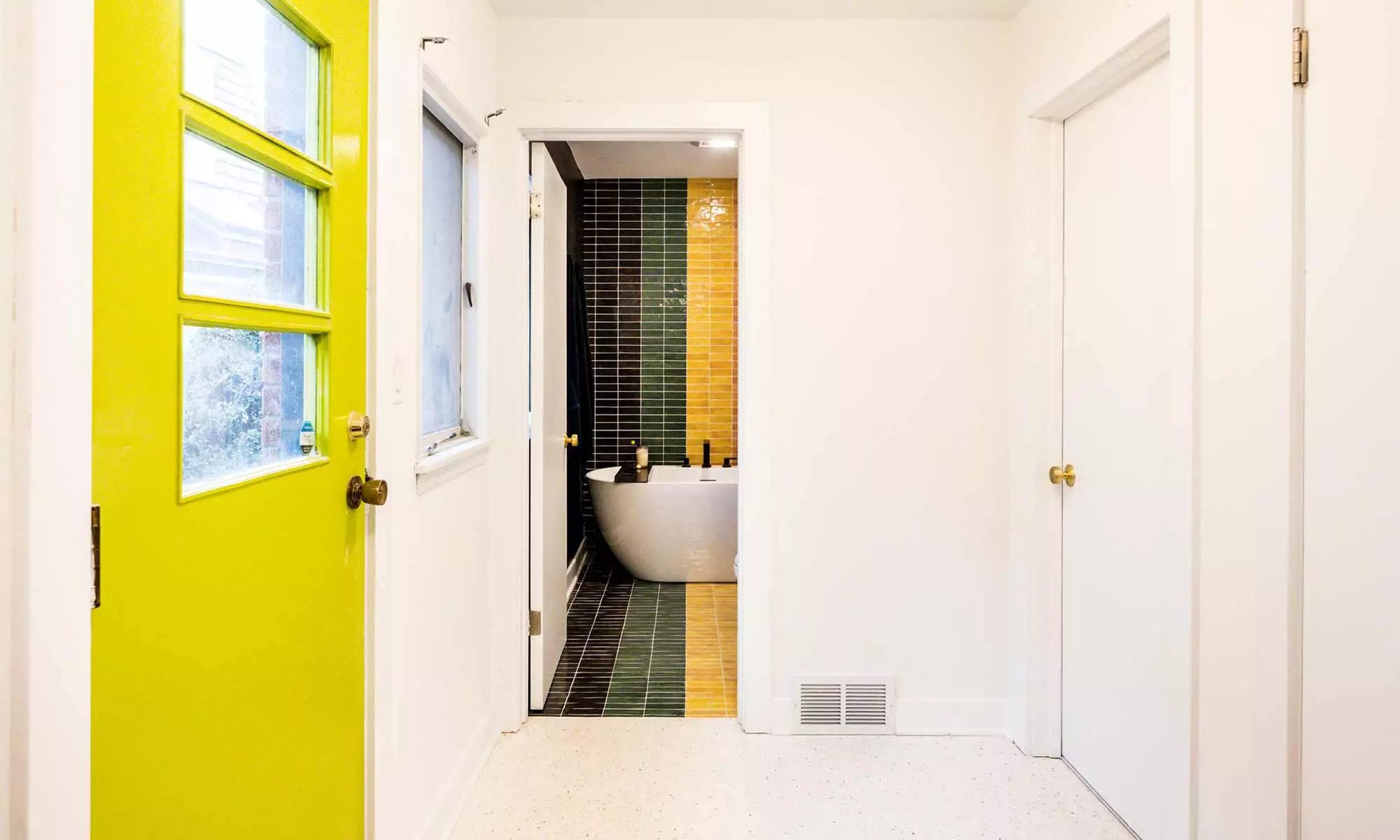 freestanding bathtub with linear textured colored wall tile in luxury mid century modern bathroom remodel in Riverside IL designed and built by LivCo view from hallway with green backdoor