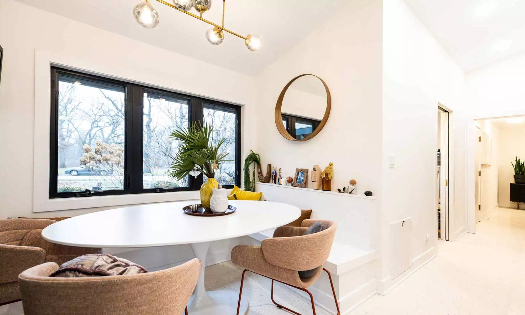 View of breakfast room with built-in seating Saarinen chairs windows and steps down in luxury MCM home remodel in Riverside IL