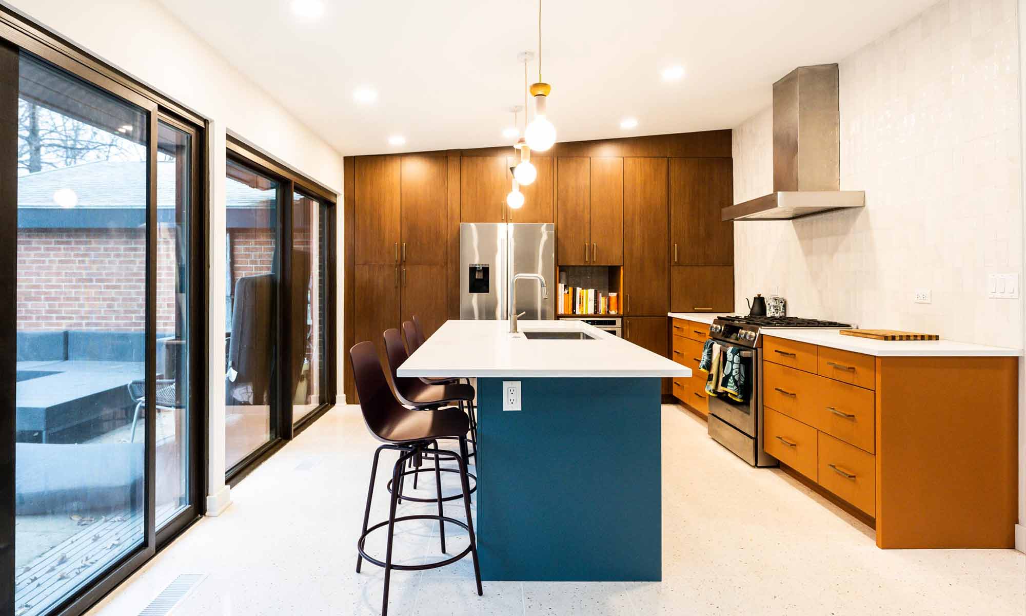 Mid century modern luxury kitchen remodel in Riverside IL by LivCo with blue island orange perimeter cabinets walnut tall cabinets and terrazzo flooring