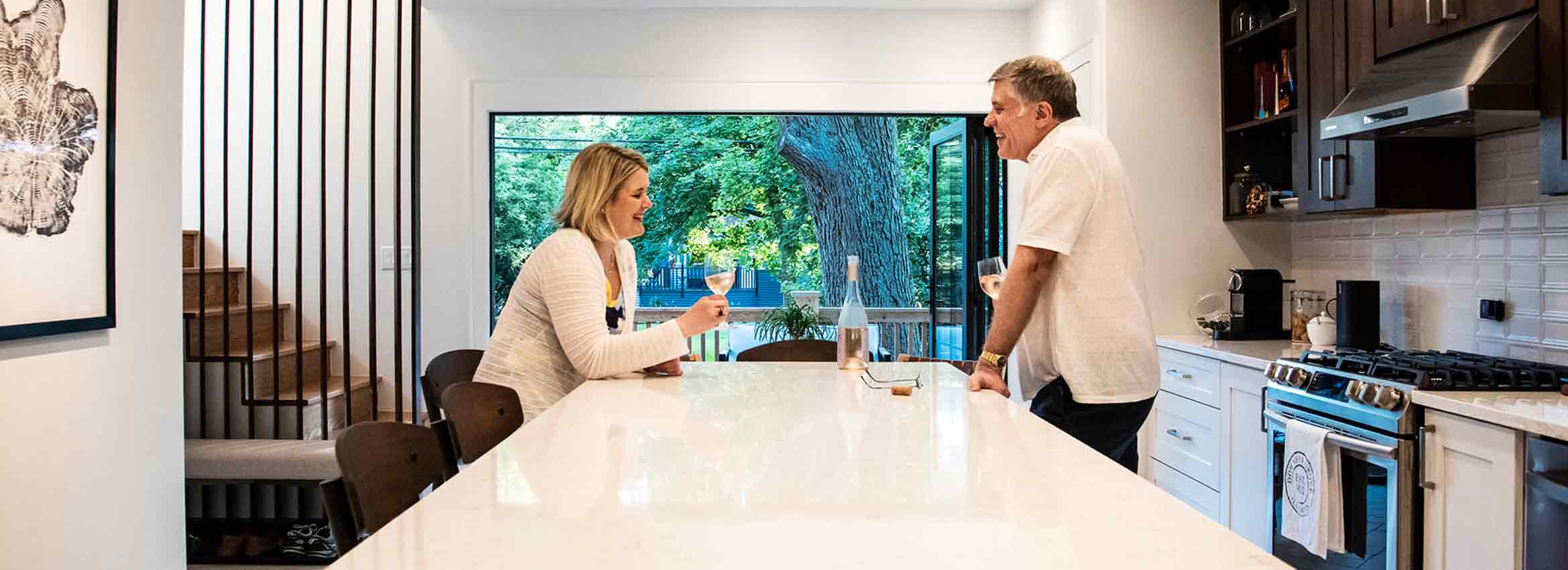 couple sharing a glass of wine at kitchen island in downers grove addition with folding doors open to back yard