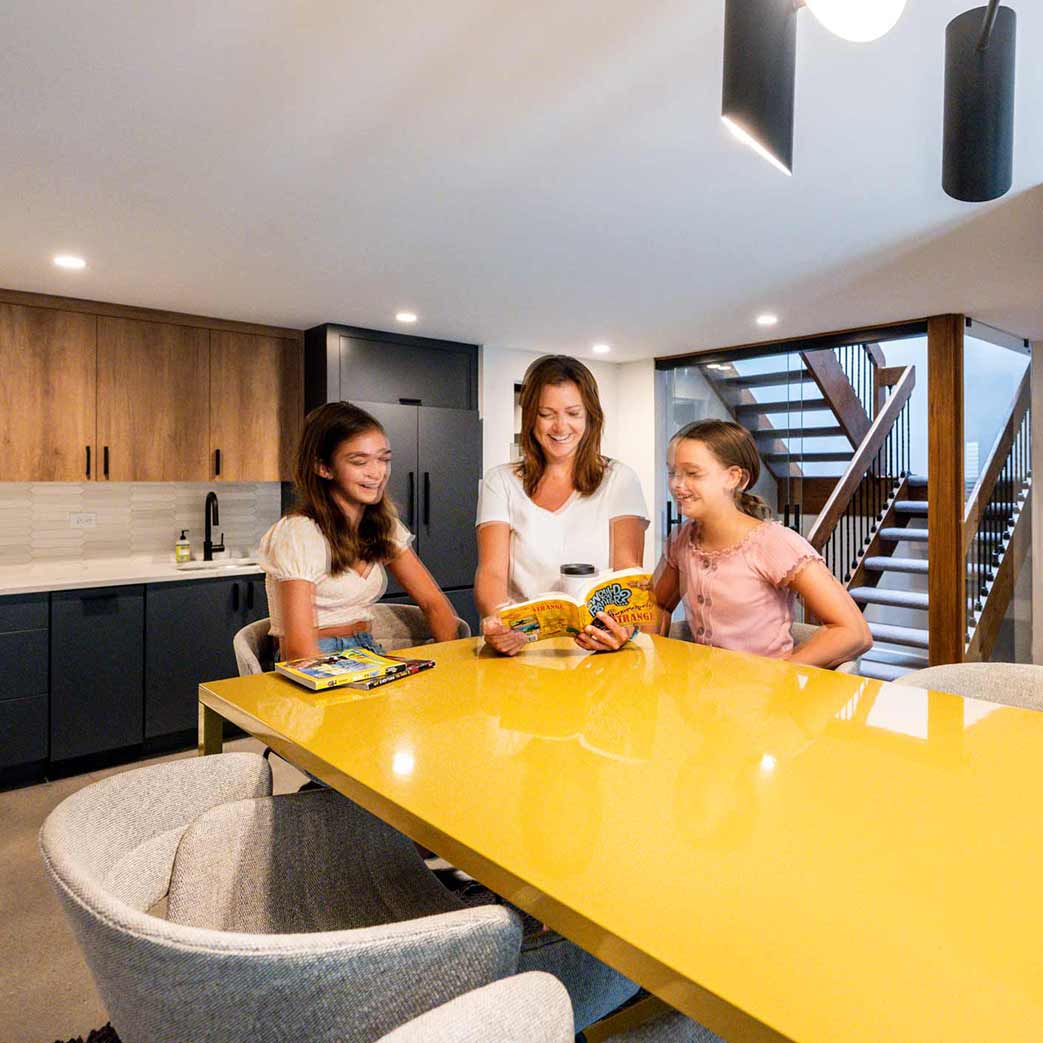 mom and daughters reading a book at yellow table in indian head park illinois luxury basement remodel