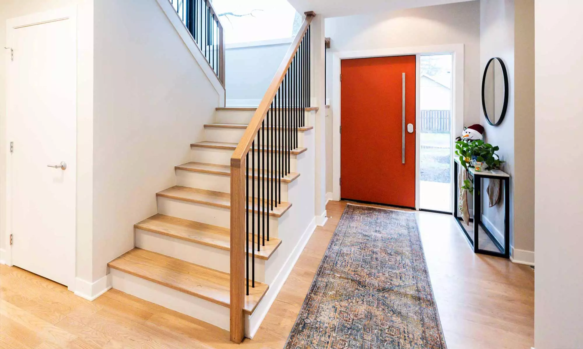 white oak stairway viewed from entrance hall in luxury second floor addition with modern orange front door