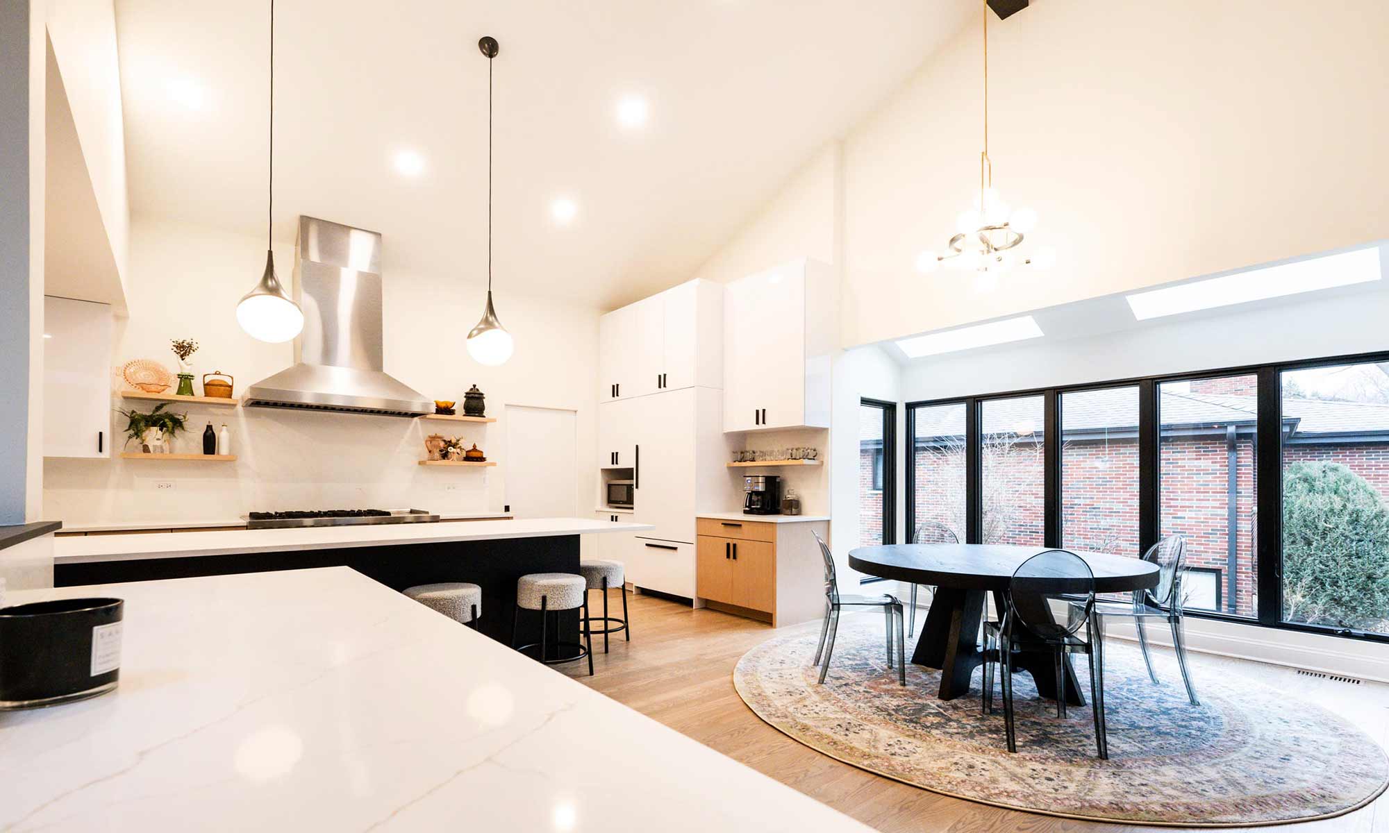 Indian Head Park luxury kithcen remodel by LivCo featuring wood, black, and gloss white modern cabinetry with view towards breakfast area